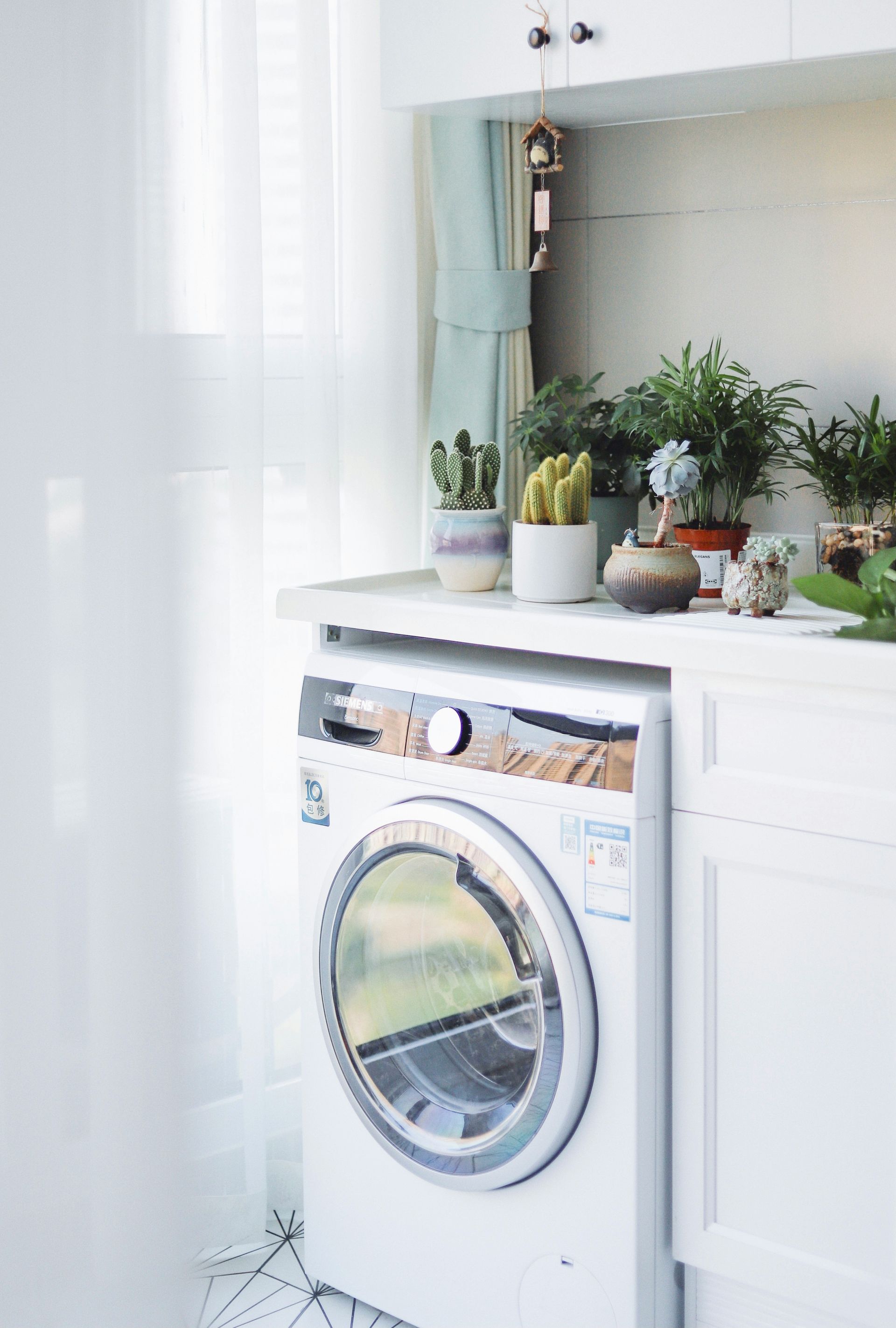 A washing machine is sitting on top of a counter next to a window.