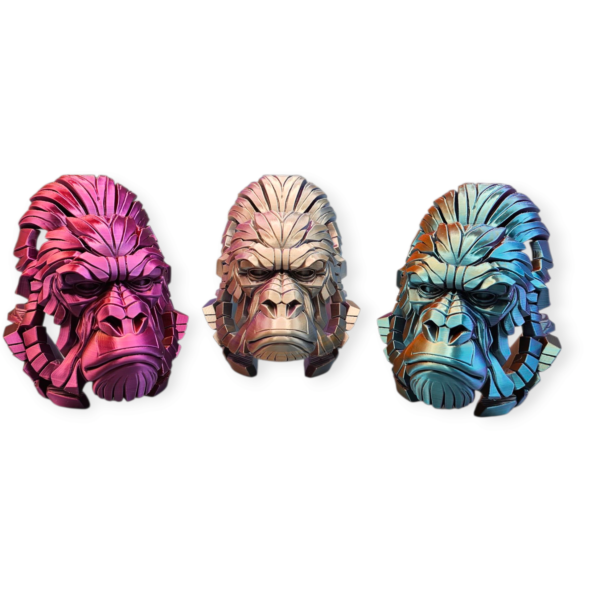 Drie sculpturen van gorillakoppen; een roze, een gouden en een blauwe, alle drie met een strenge uitdrukking.