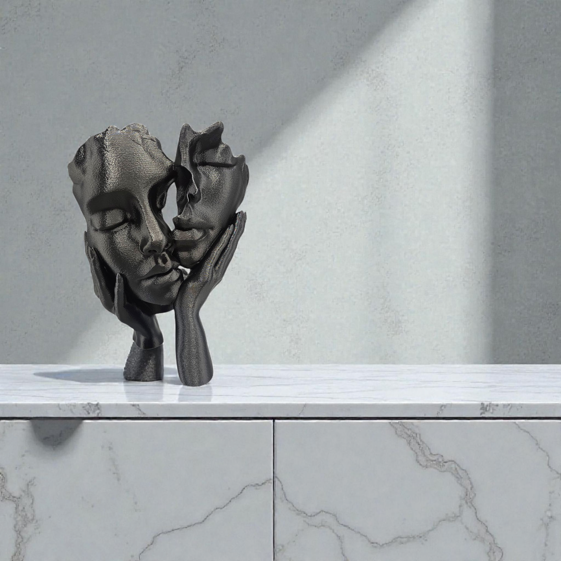 Zwarte sculptuur van twee in elkaar verstrengelde gezichten die elkaar lijken aan te raken; handen omarmen de gezichten, geplaatst op een marmeren ondergrond.