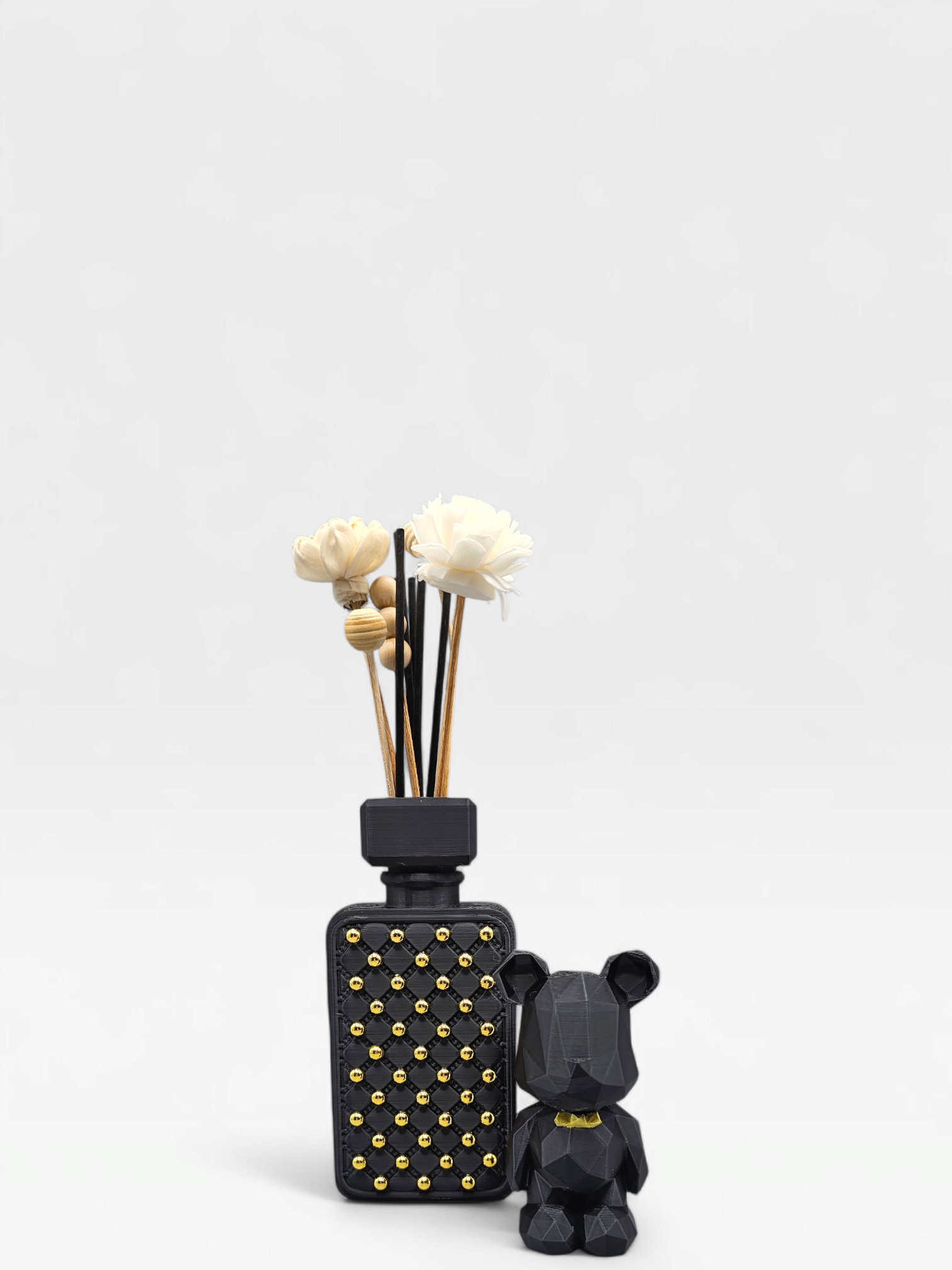 Zwarte geometrische vaas met rietstengels en een berenfiguurtje op een gouden schaal, in de woonkamer.