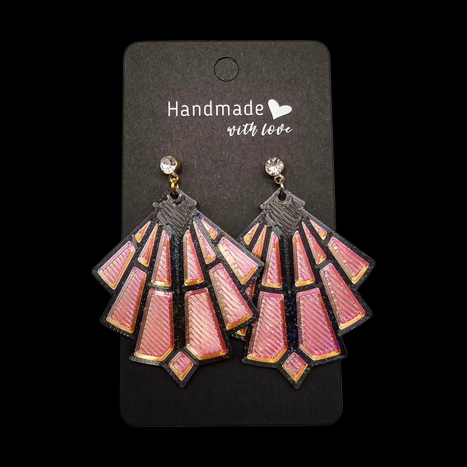 Roze en zwarte geometrische oorbellen op een zwart kaartje met de tekst "Handgemaakt met liefde".