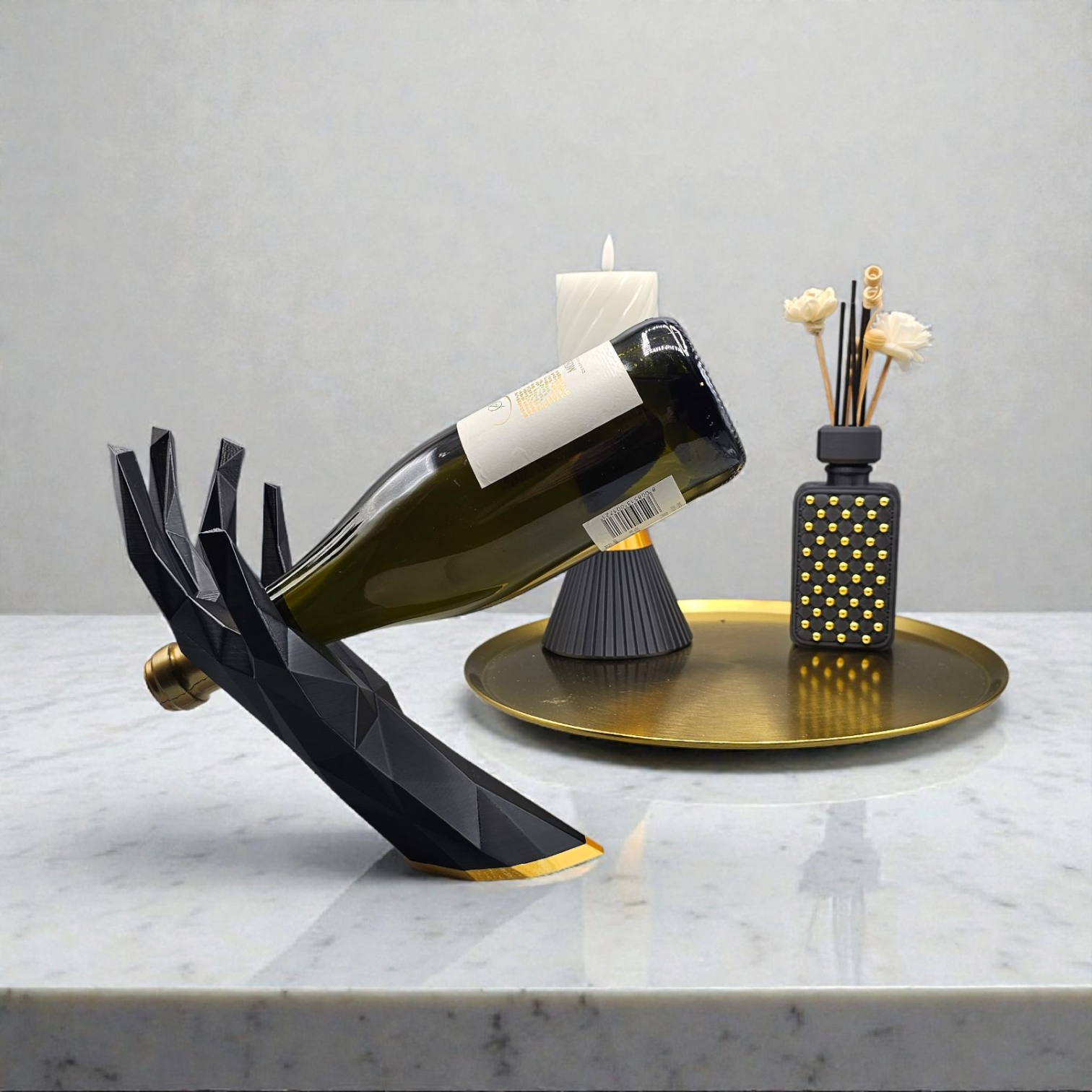Zwarte, geometrische, handvormige wijnhouder met daarop een wijnfles op een houten tafel, met kaarsen en een dienblad op de achtergrond.