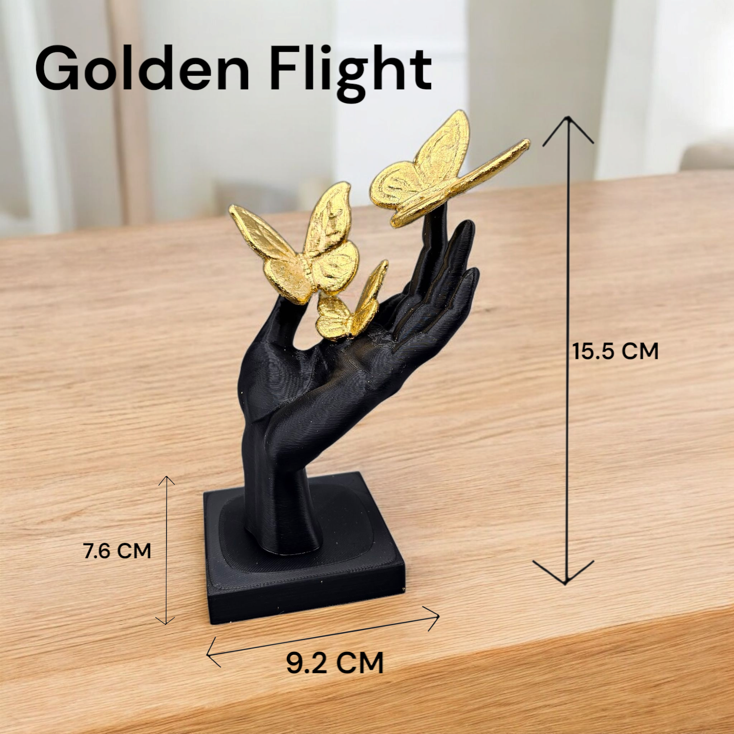 Een zwart handbeeldje met drie gouden vlinders op een houten tafel. Afmetingen: 15,5 cm hoog, 9,2 cm breed, 7,6 cm diep.