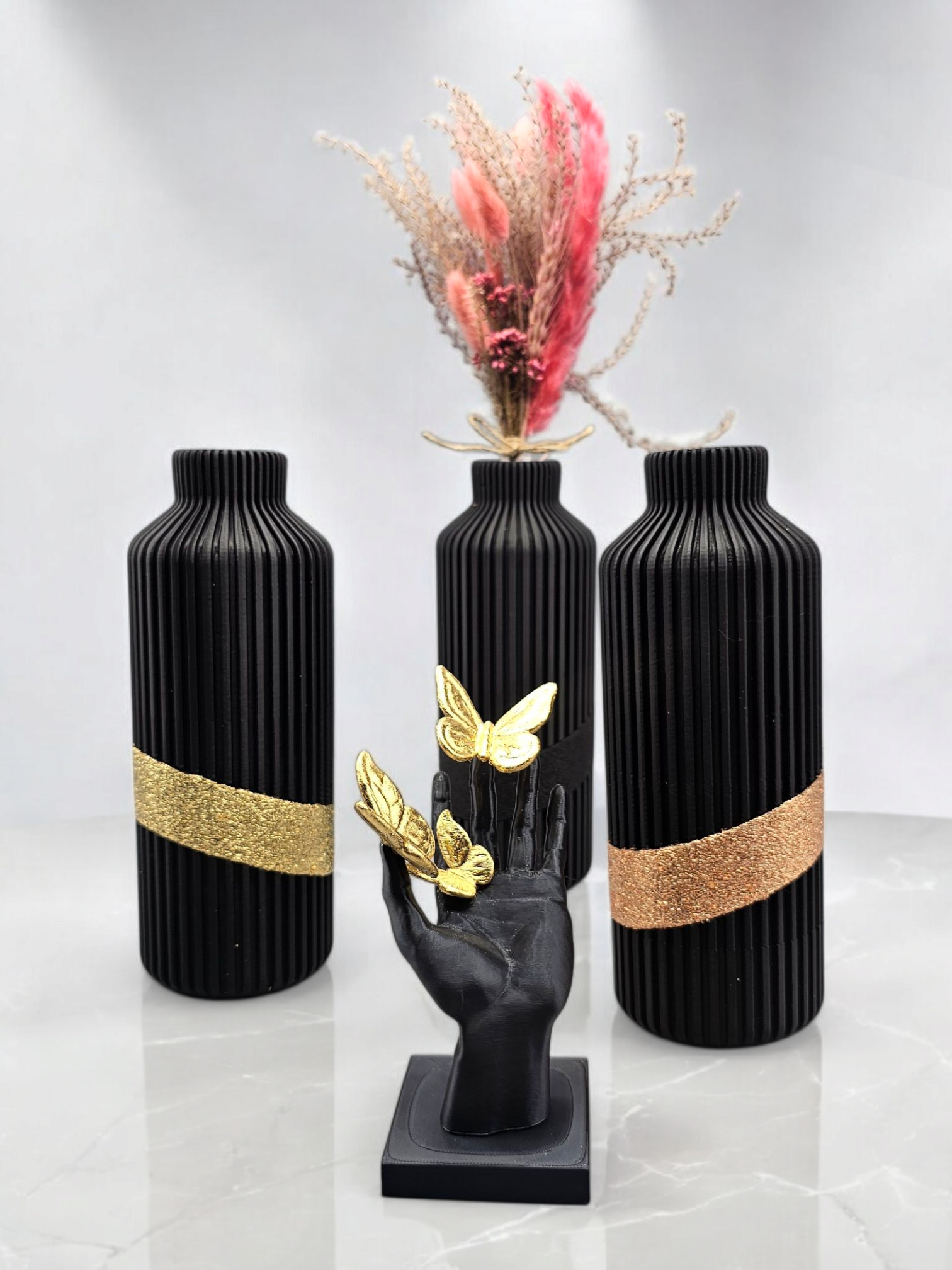 Een zwart handbeeldje met drie gouden vlinders op een houten tafel. Afmetingen: 15,5 cm hoog, 9,2 cm breed, 7,6 cm diep.