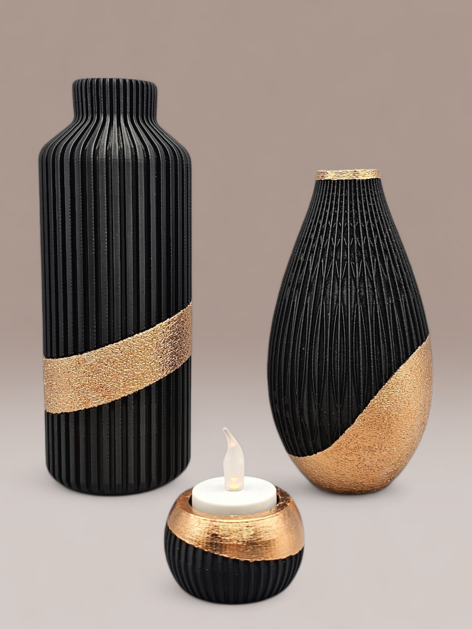 Een decoratieve tafelsetting: zwarte en gouden vazen ​​met gedroogde bloemen en een kaars op een rond dienblad in een woonkamer.