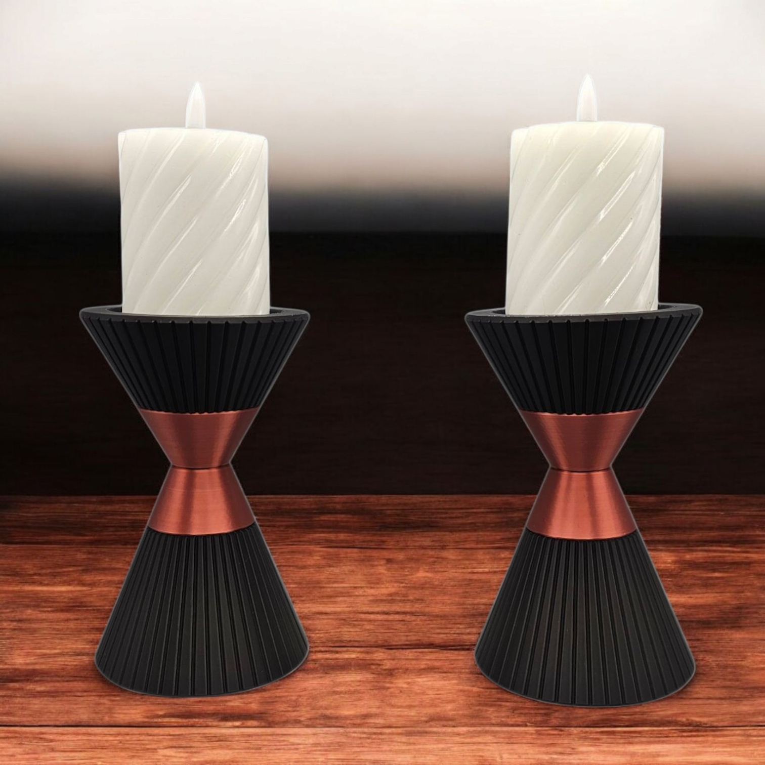 Twee kandelaars met witte kaarsen; zwarte voet en koperkleurig middengedeelte; op een houten ondergrond.