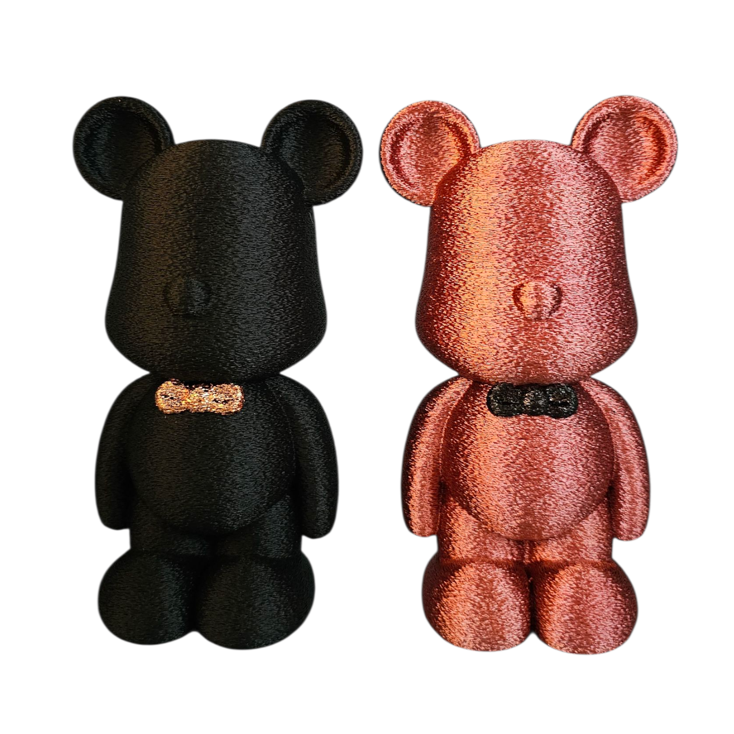 Zwarte teddybeer met gouden strik, 18 cm hoog, naast roze bloemen.