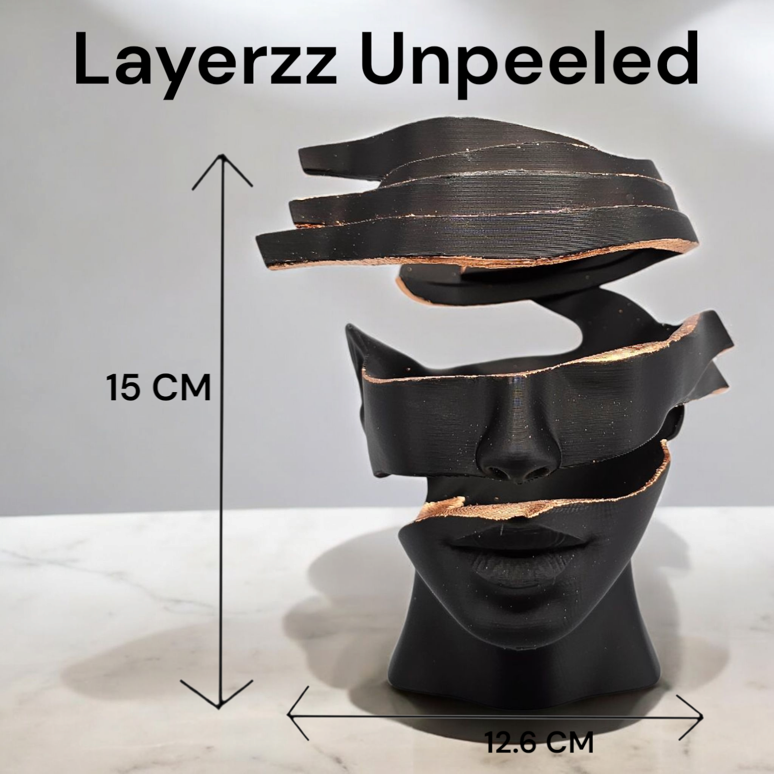 Decoratie in zwart en goud: sculptuur van een doorgesneden gezicht, kaars, vaas met een arrangement van gedroogde bloemen op een dienblad.