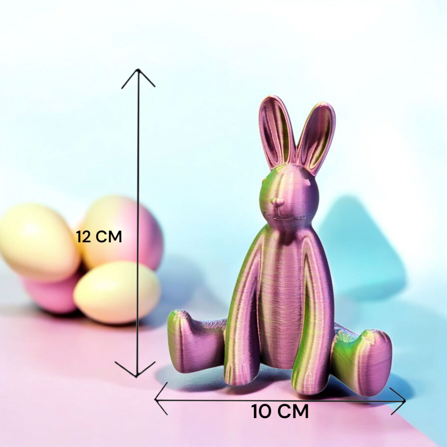 Drie iriserende paashaasjes op een houten tafel, omringd door pastelkleurige eieren en bloemen in een keuken.