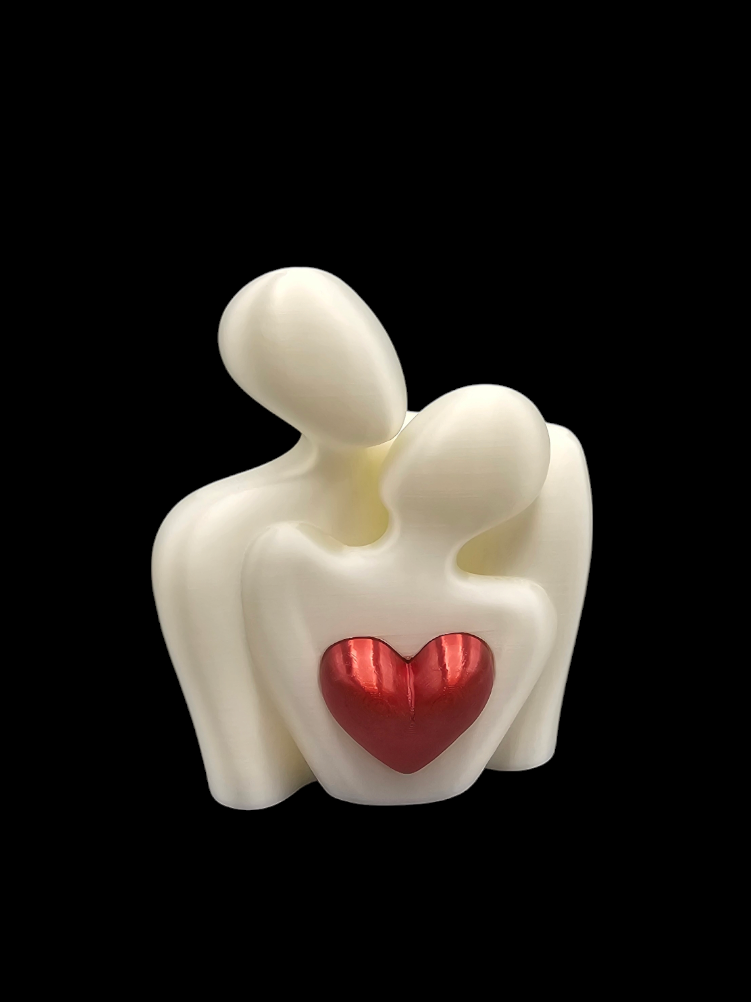 Crèmekleurig beeld van twee omhelzende figuren met een rood hart in het midden.