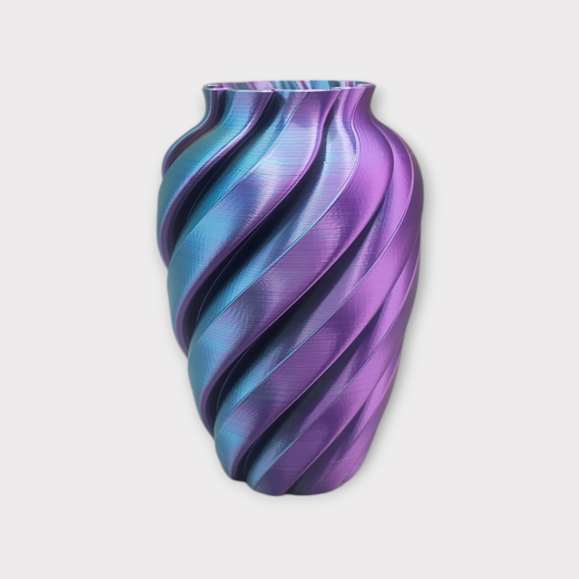 Een 3D-geprinte vaas met een spiraalvormige, geribbelde textuur en een kleurverloop van metallic blauw naar paars.