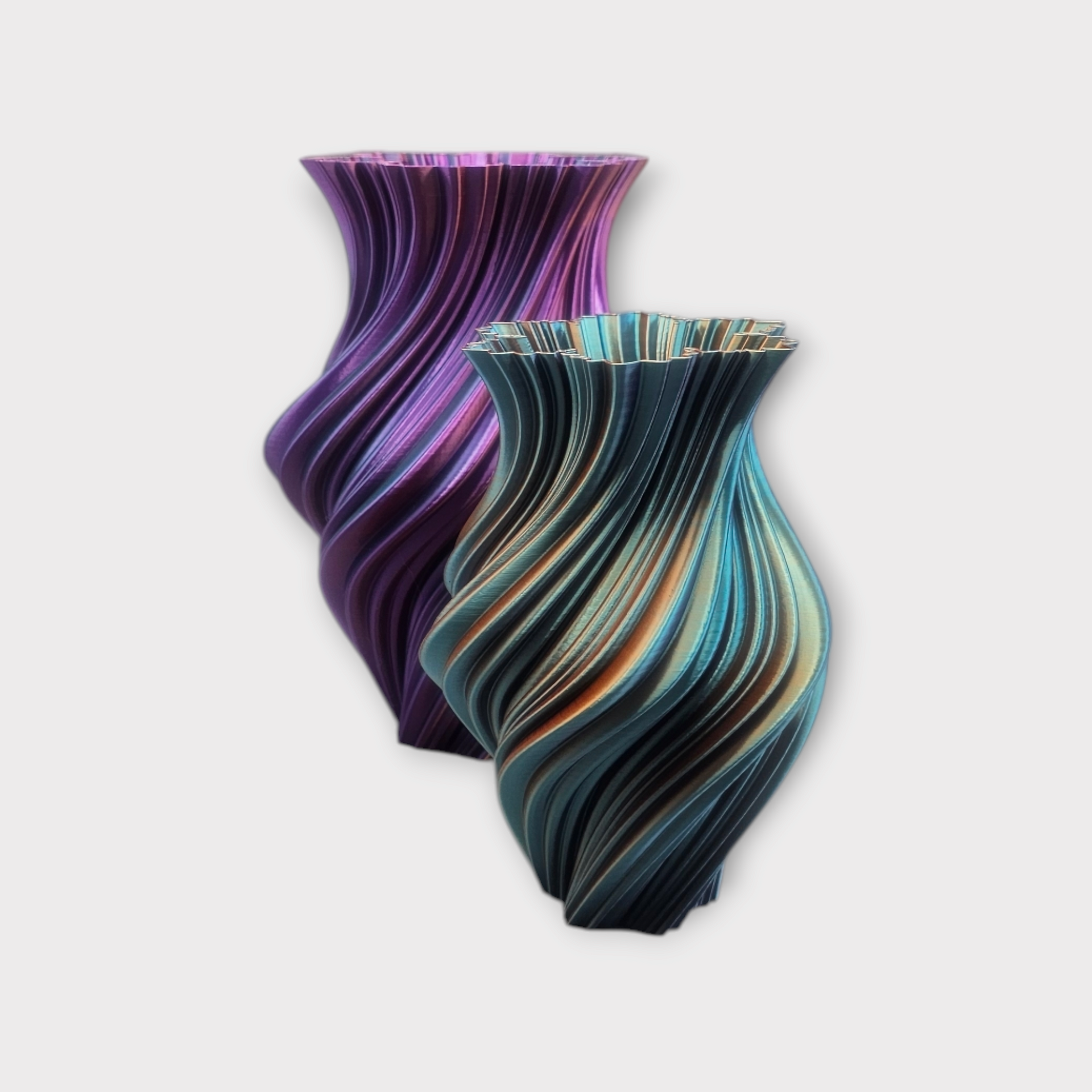 Twee iriserende, gedraaide 3D-geprinte vazen; een paarse en een blauwe met oranje accenten.