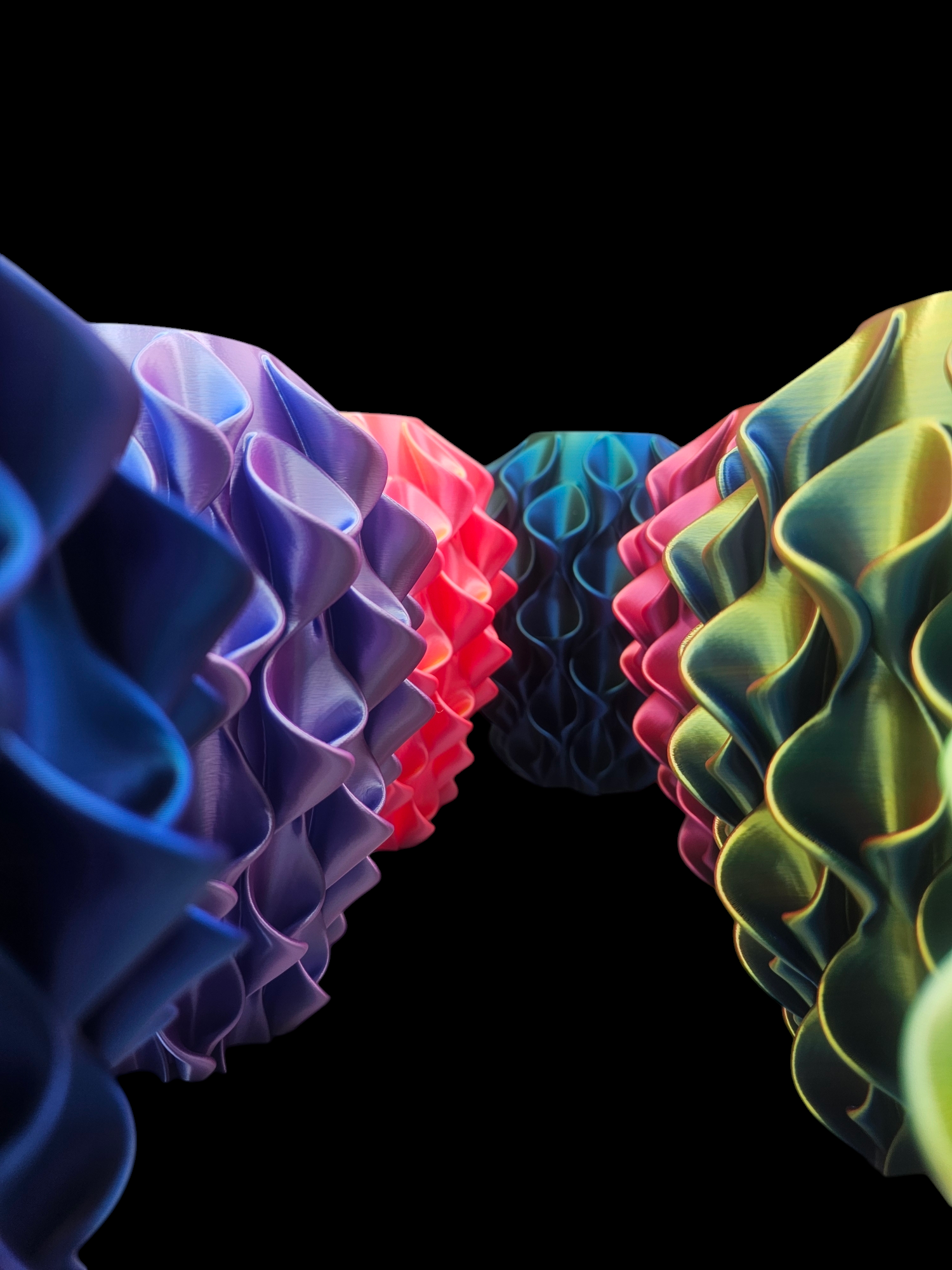 Golvende, honingraatachtige structuren in blauw, rood en groen tegen een zwarte achtergrond.