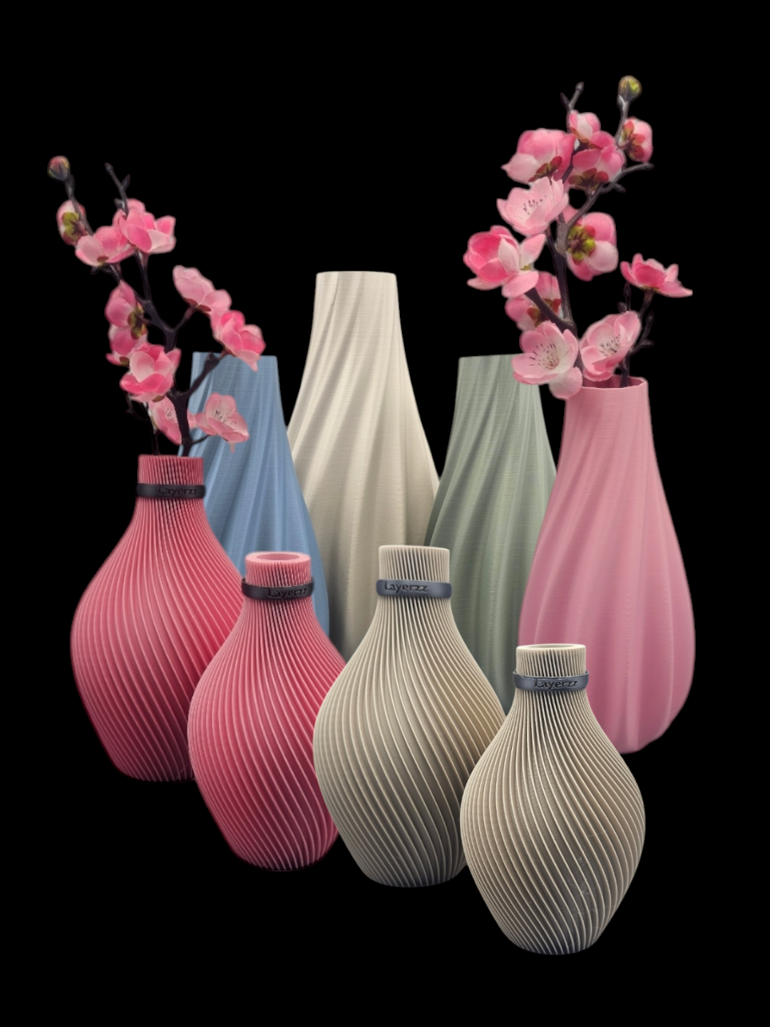 Assortiment van kleurrijke, wervelende vazen met roze bloemen op een zwarte achtergrond.