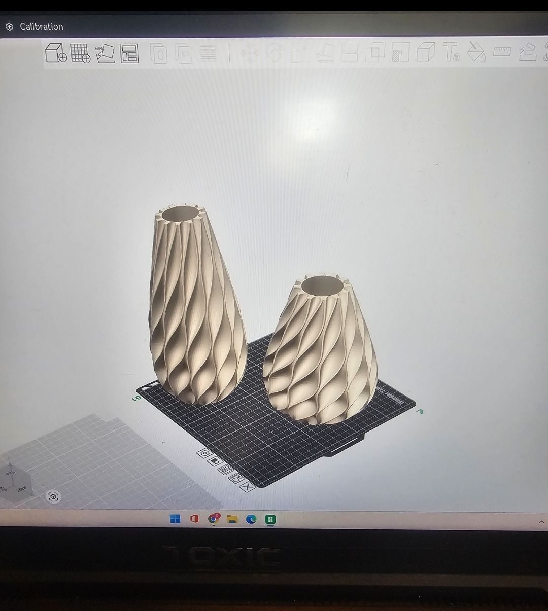 Two beige, spiral-patterned vases on a dark, patterned surface, in a computer design program.