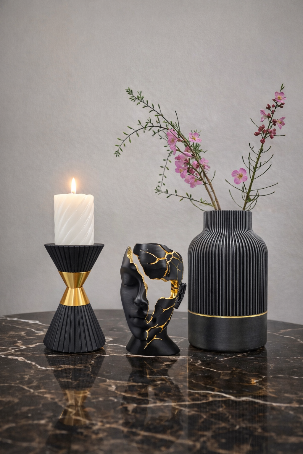 Twee zwarte vazen ​​met pampasgras op een marmeren tafel, omlijst door een gouden spiegel.