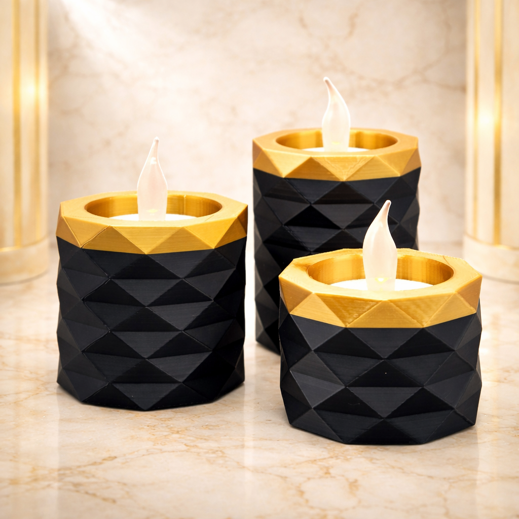 Drie geometrische LED-kaarsen in zwart en goud op een marmeren ondergrond.