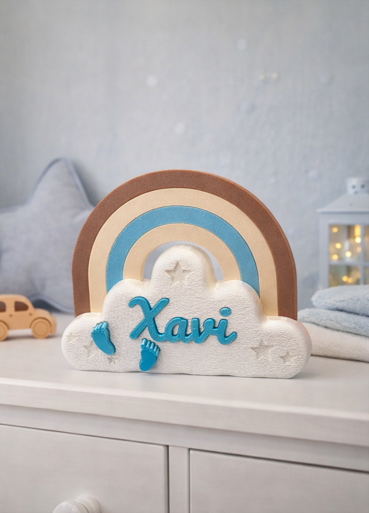 Een decoratief plankbordje in de vorm van een witte wolk en een bruin-blauwe regenboog, met de naam 