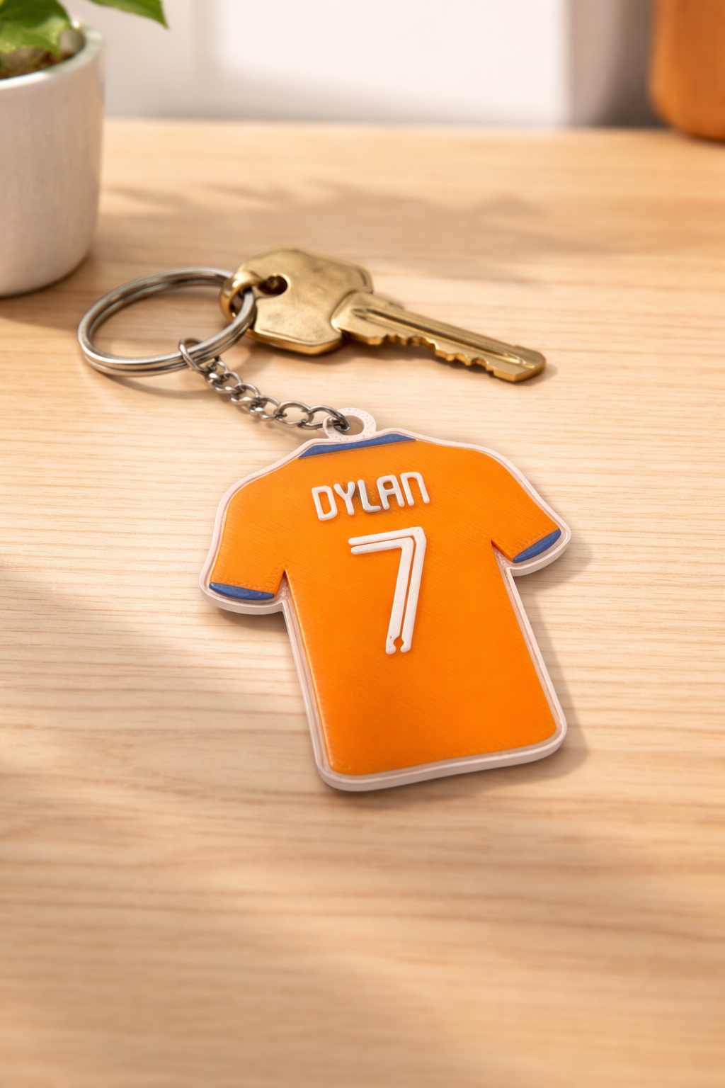 Een oranje sleutelhanger in de vorm van een sportshirt met de naam 