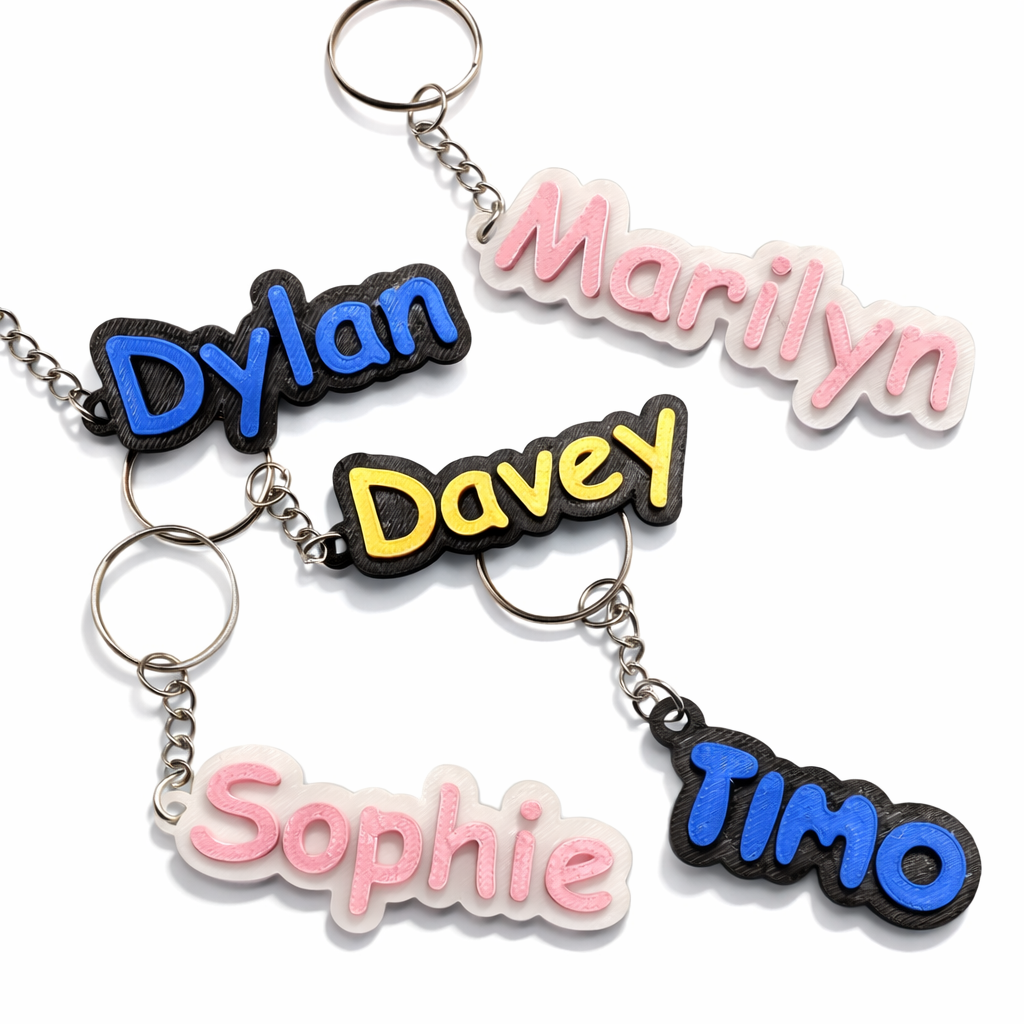 Vijf kleurrijke sleutelhangers met gepersonaliseerde namen – Marilyn, Dylan, Davey, Sophie en TIMO – afgebeeld op een effen witte achtergrond.