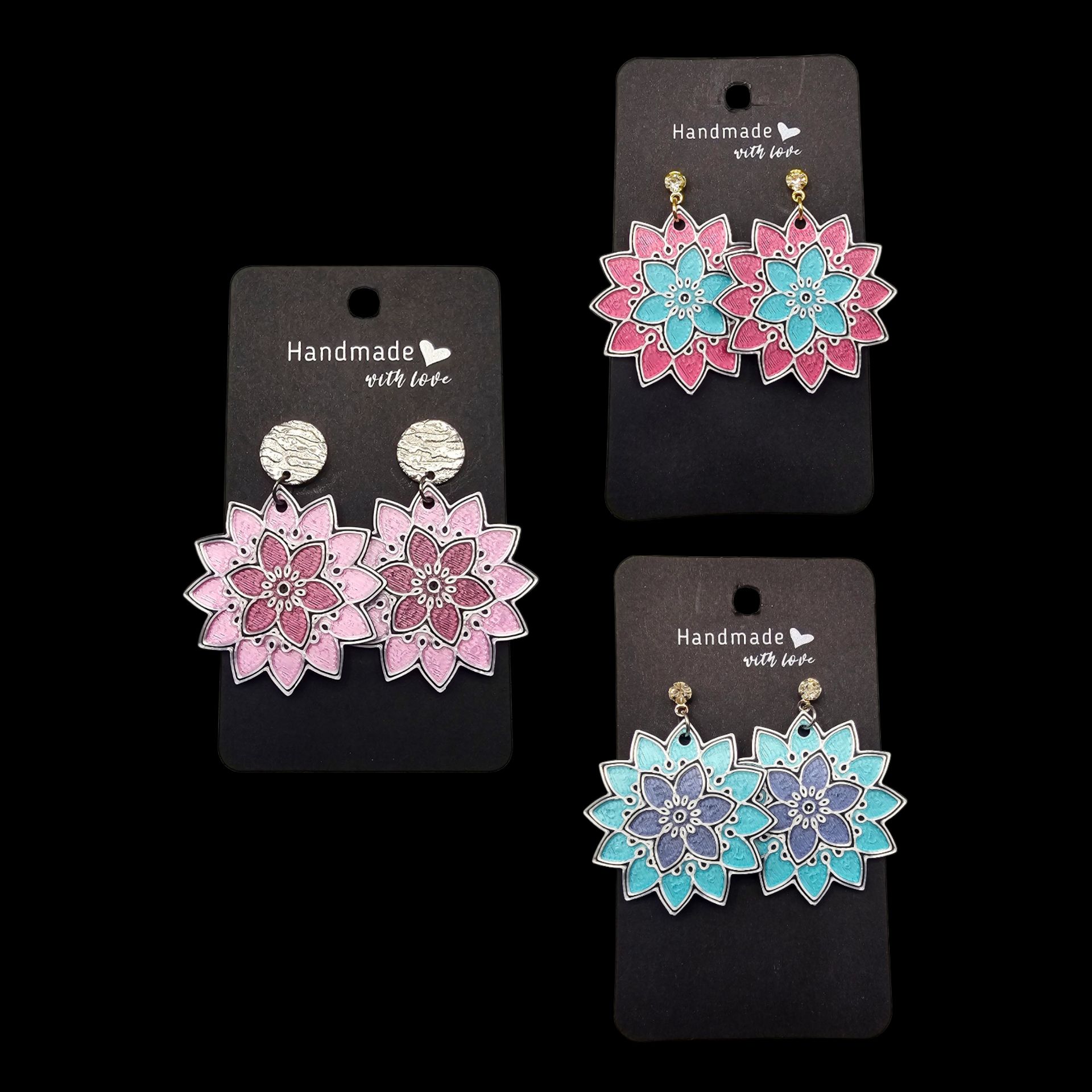 Drie paar kleurrijke, bloemvormige oorbellen, tentoongesteld op zwarte kaartjes.