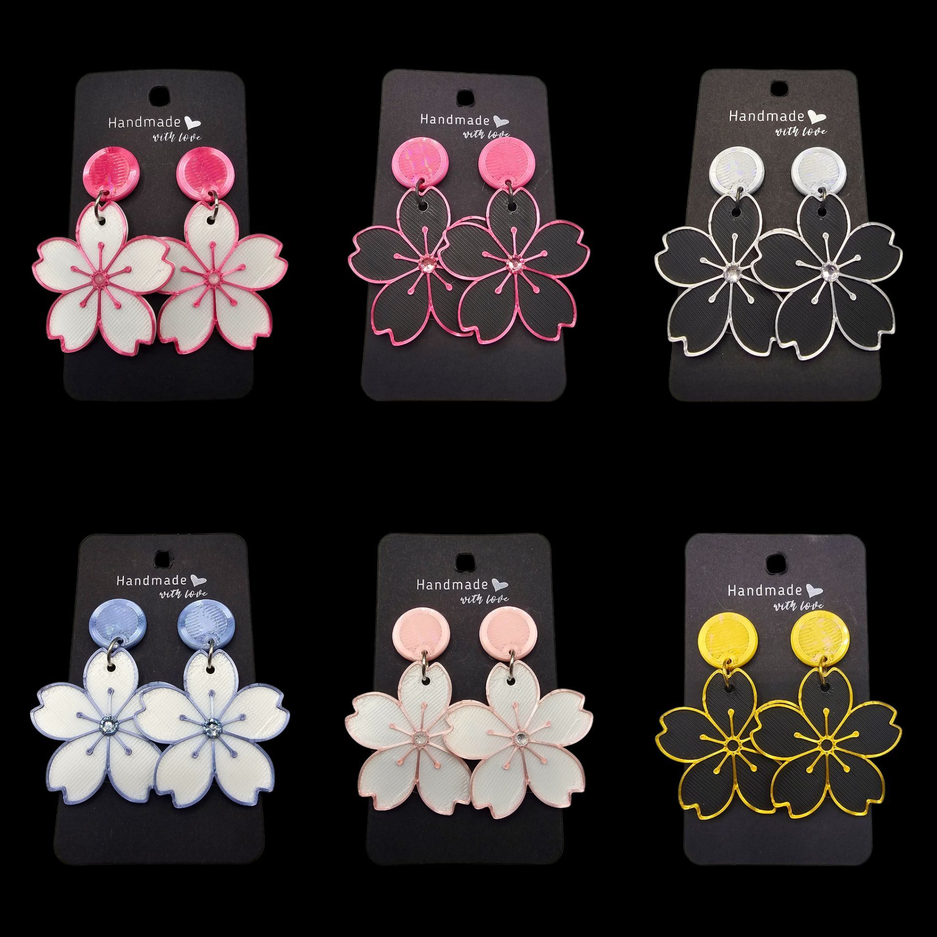 Zes paar bloemvormige oorbellen op zwarte kaartjes; in de kleuren roze, wit, zilver, blauw, perzik en geel.