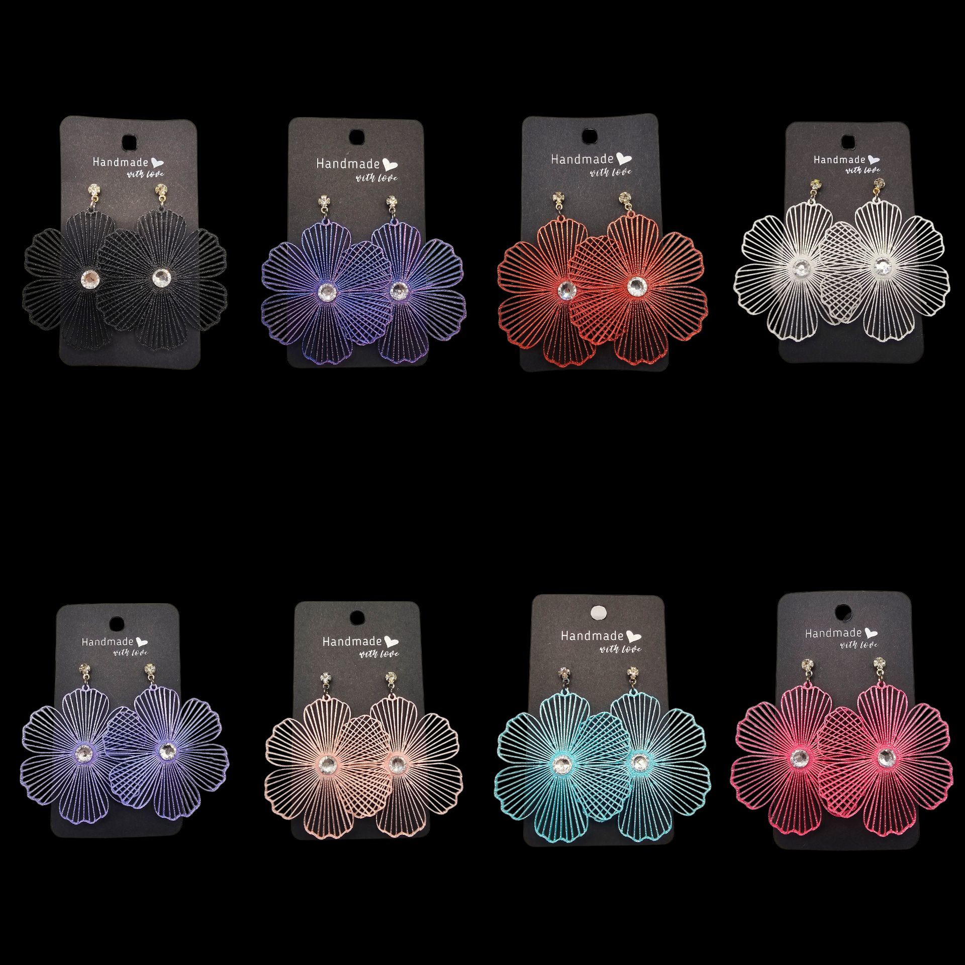 Acht paar oorbellen met bloemmotief in verschillende kleuren, gepresenteerd op zwarte kaartjes tegen een zwarte achtergrond.