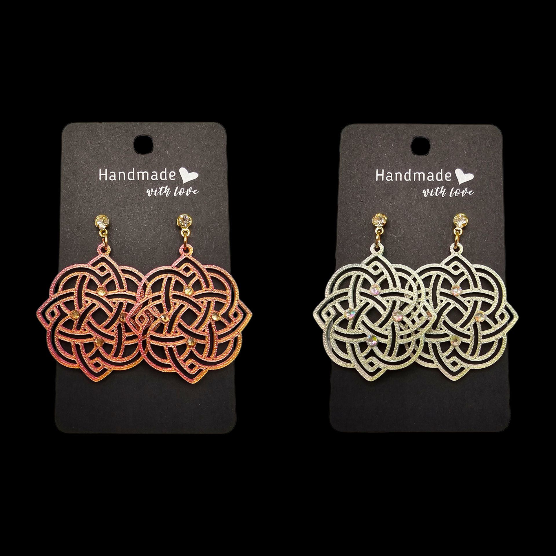 Twee paar oorbellen met Keltische knopen op zwarte kaartjes, één in roségoud en één in goud.