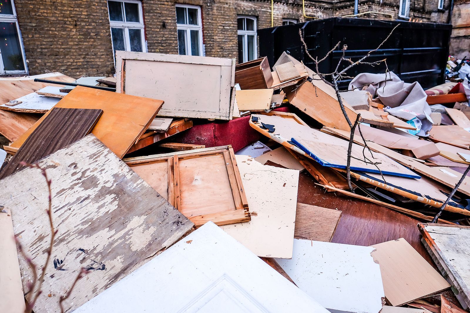 A pile of cardboard and wood is sitting in front of a brick building.
