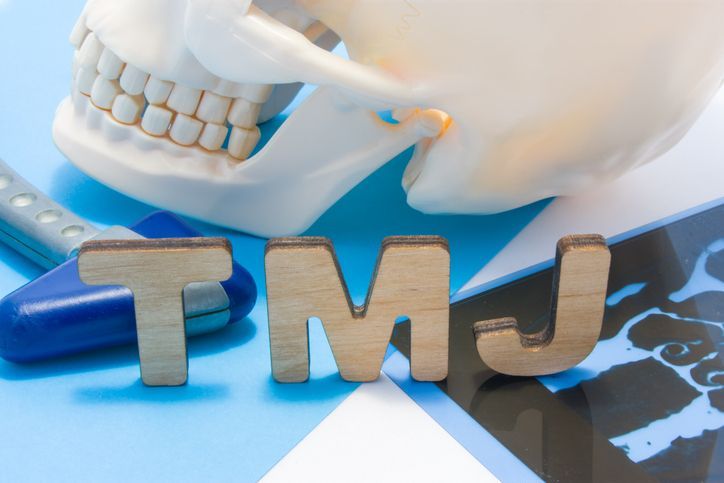 Close-up of a skull, TMJ letters, x-ray, and medical tools, indicating TMJ diagnosis.