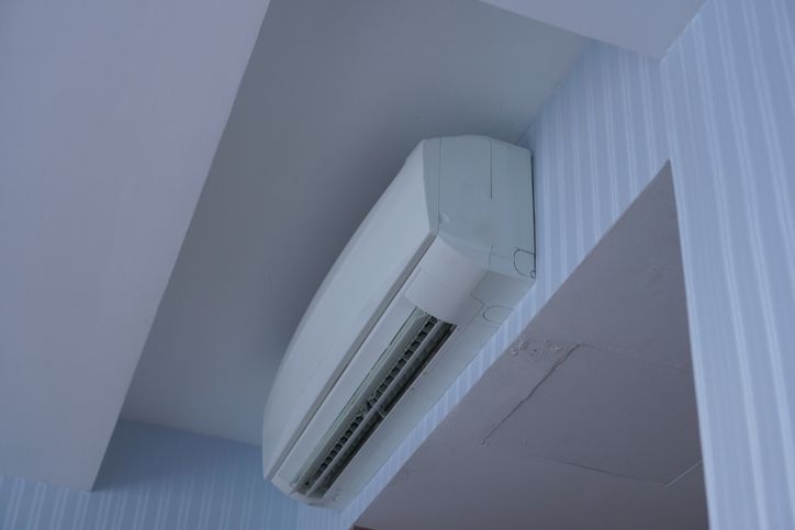 Condizionatore d'aria bianco montato su una parete azzurra con finiture bianche.