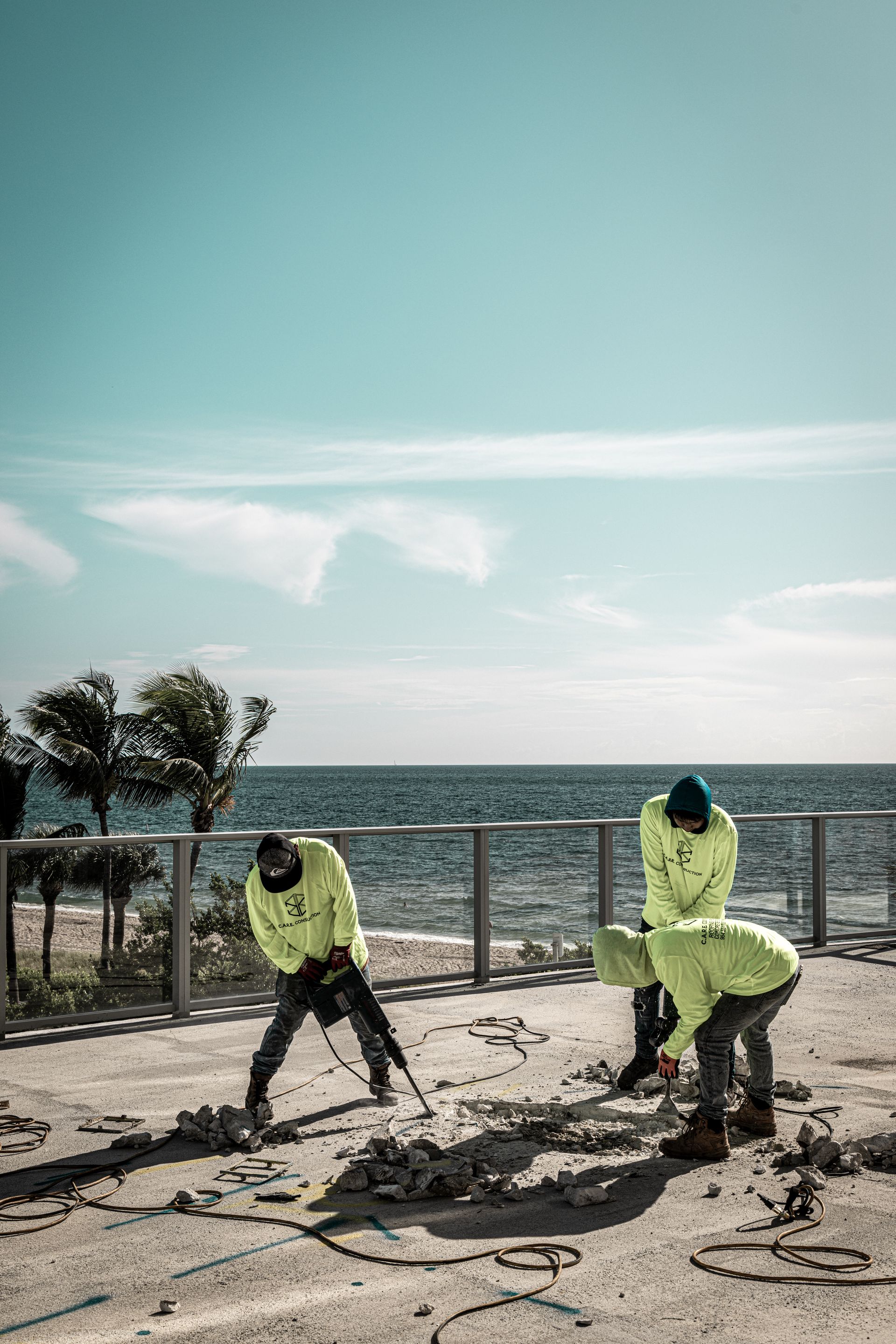 A group of construction workers are working on a beach near the ocean.