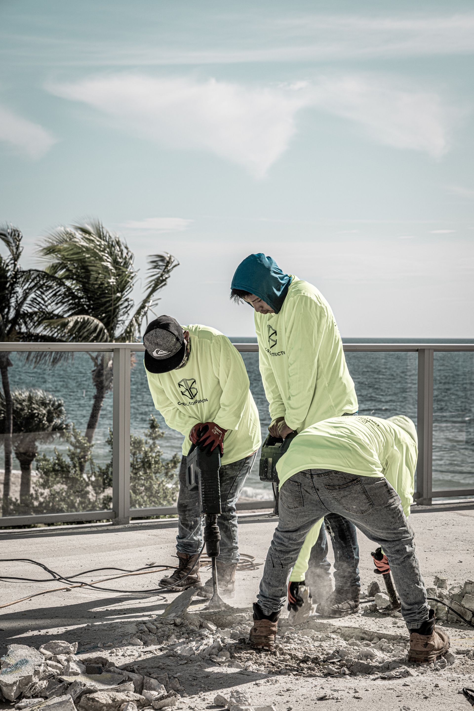 A group of construction workers are working on a beach near the ocean.