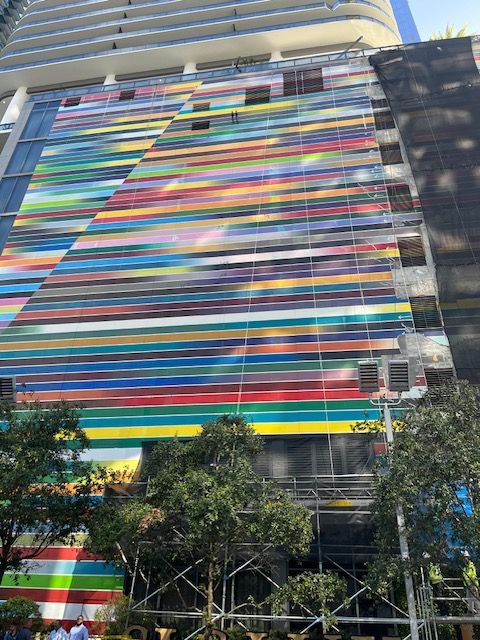 A large colorful mural is being painted on the side of a building.
