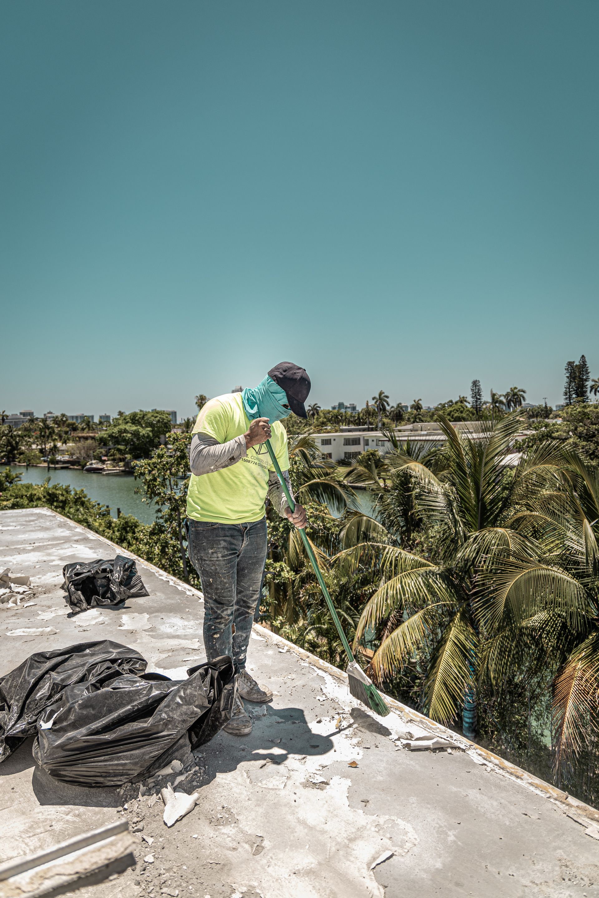 A man is standing on top of a roof with a broom.
