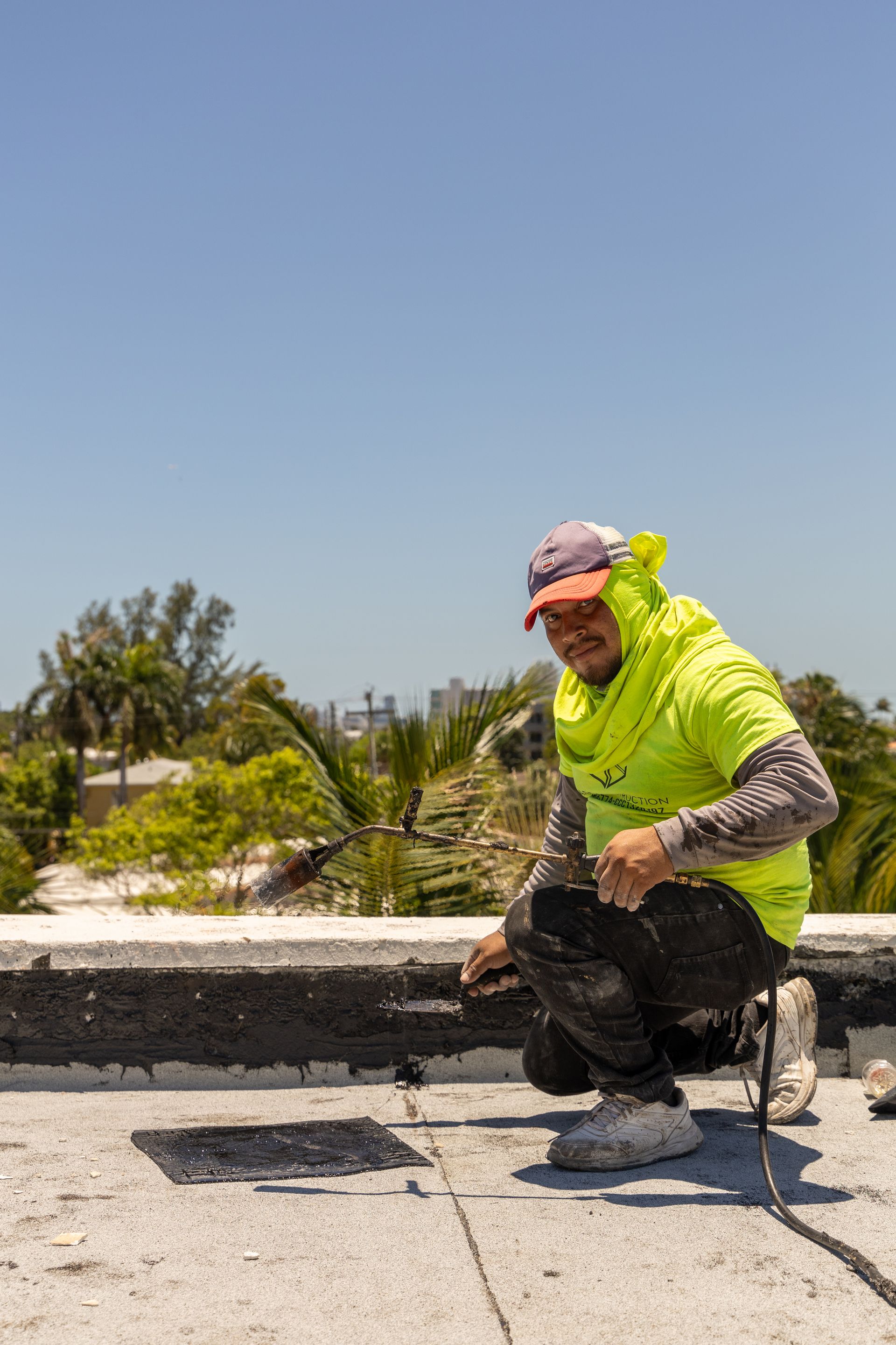 A man is kneeling on the roof of a building.