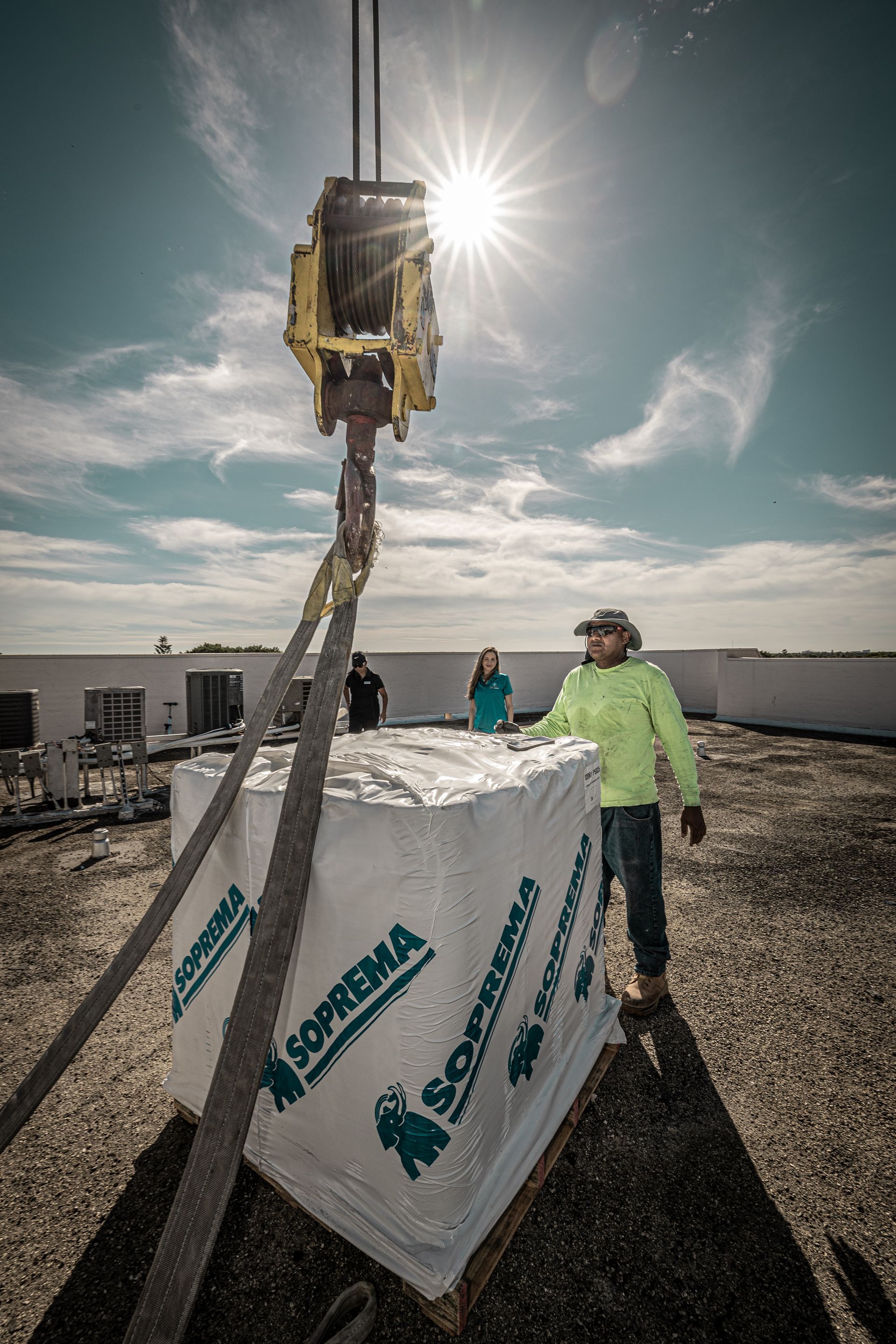 A man is standing next to a crane on top of a building.