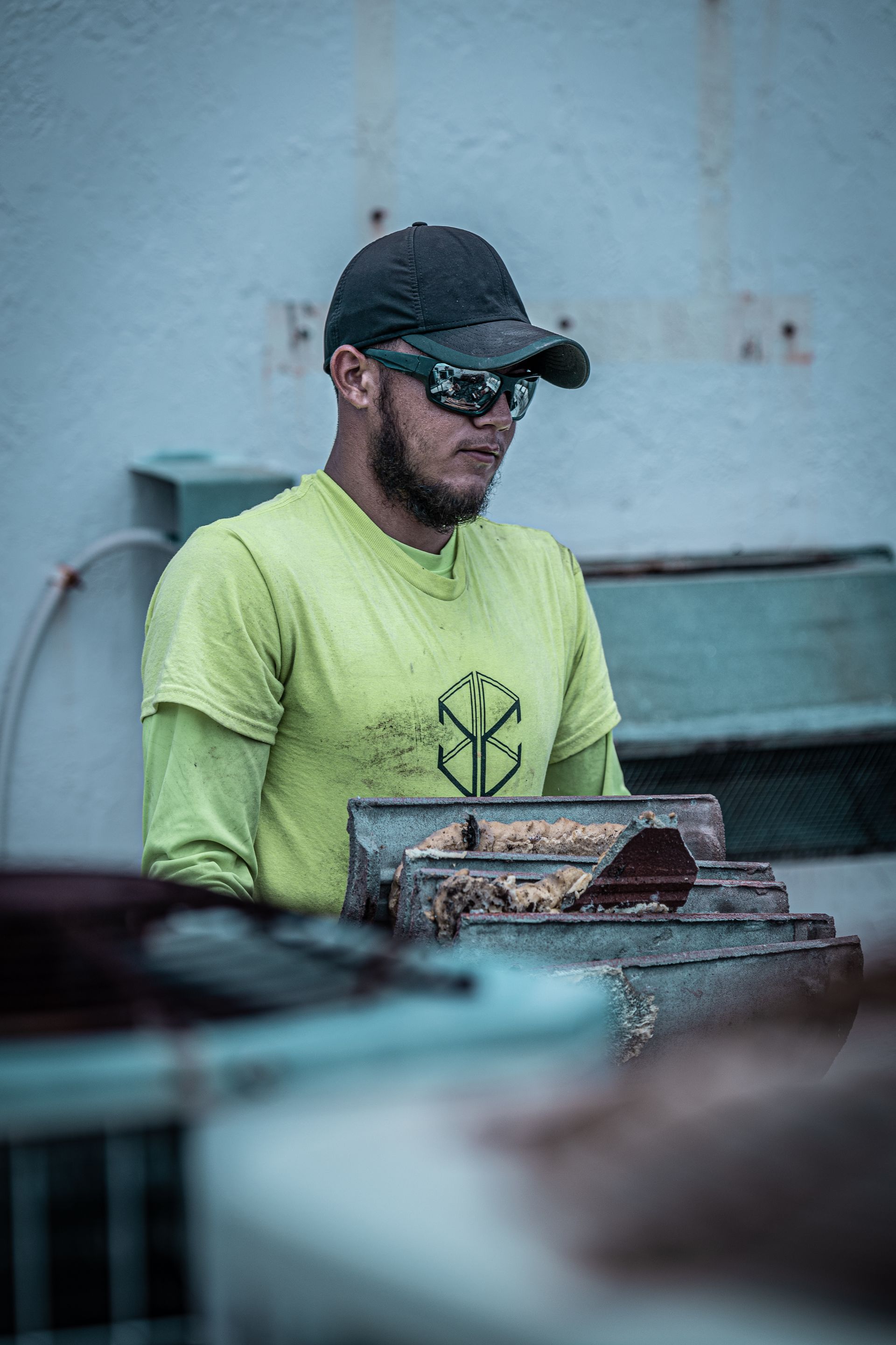 A man wearing sunglasses and a hat is standing in front of a machine.