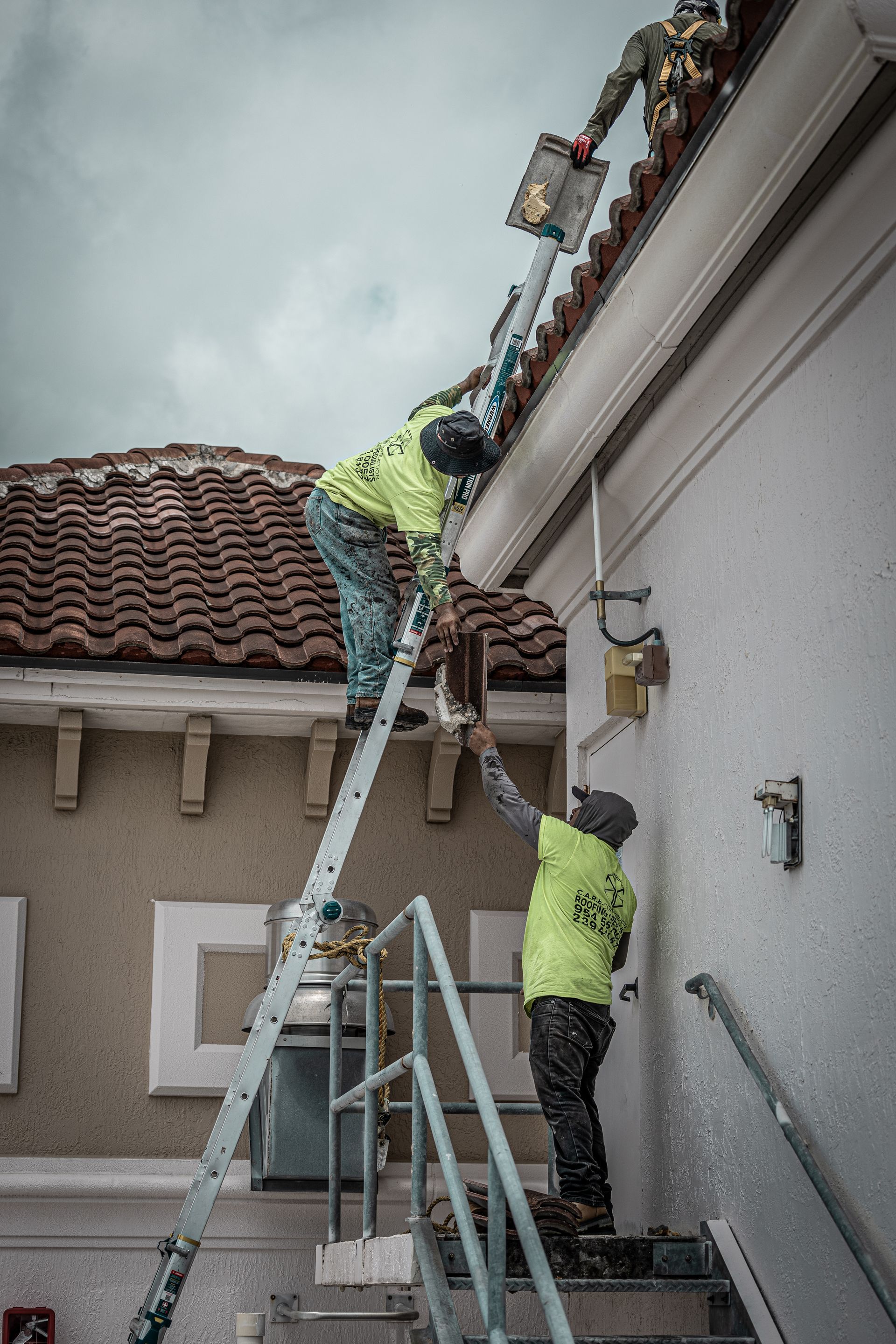 Two men are painting the side of a building.