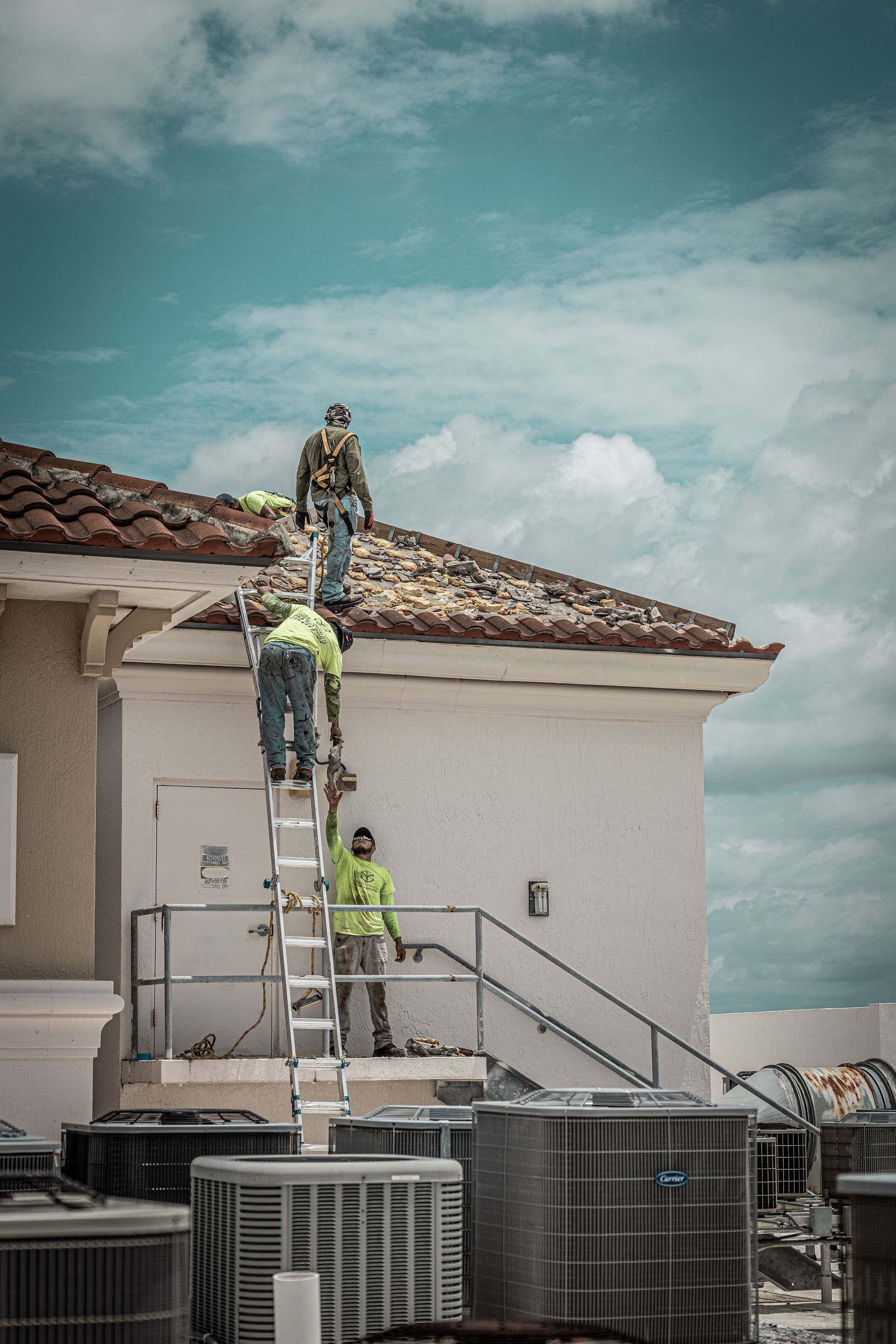 A group of construction workers are working on the roof of a building.