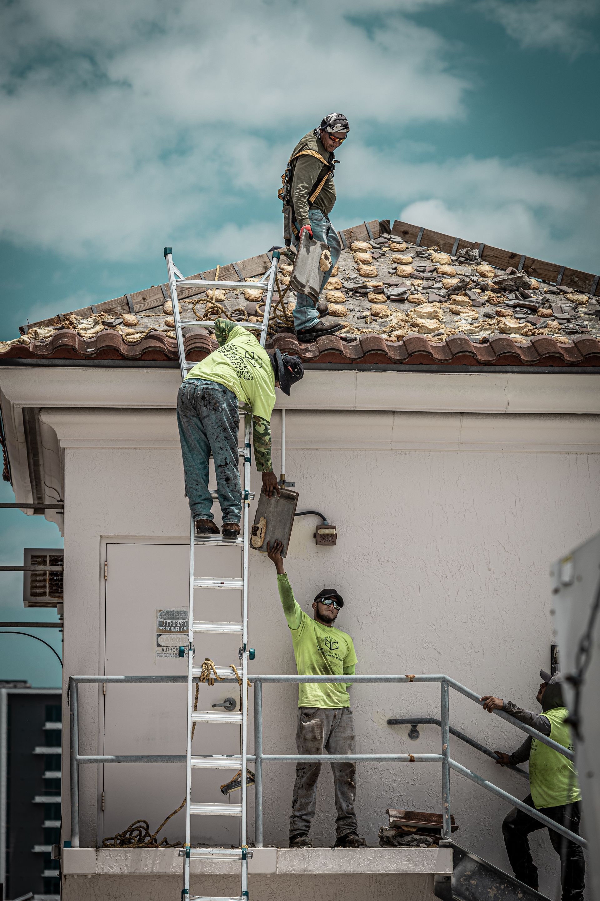 A group of construction workers are working on the roof of a building.