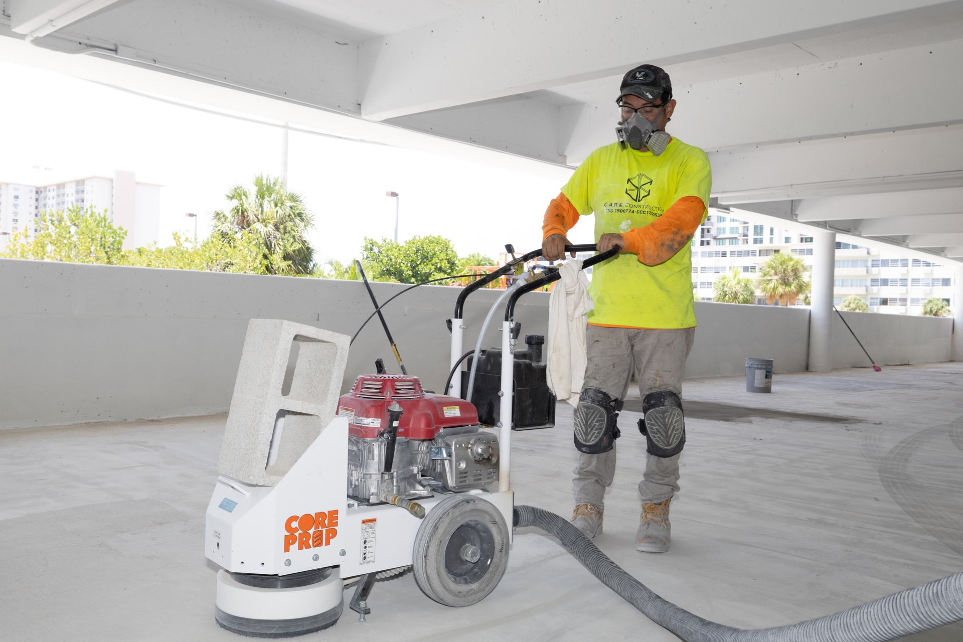 A man wearing a gas mask is using a grinder on a concrete floor.