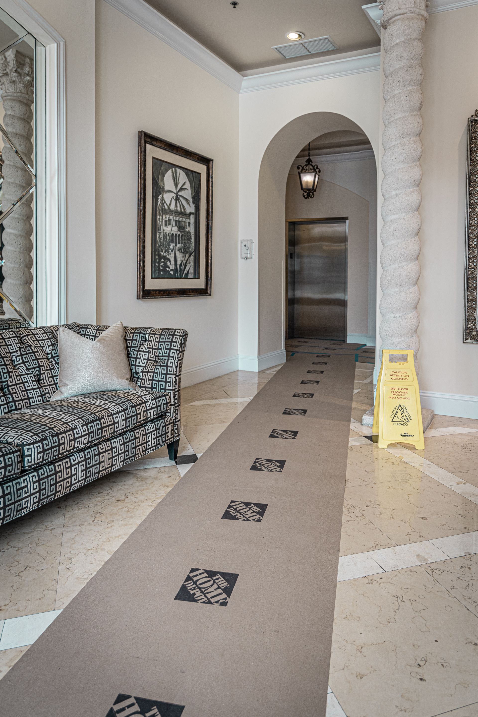 A hallway with a couch and a yellow caution sign on the floor.