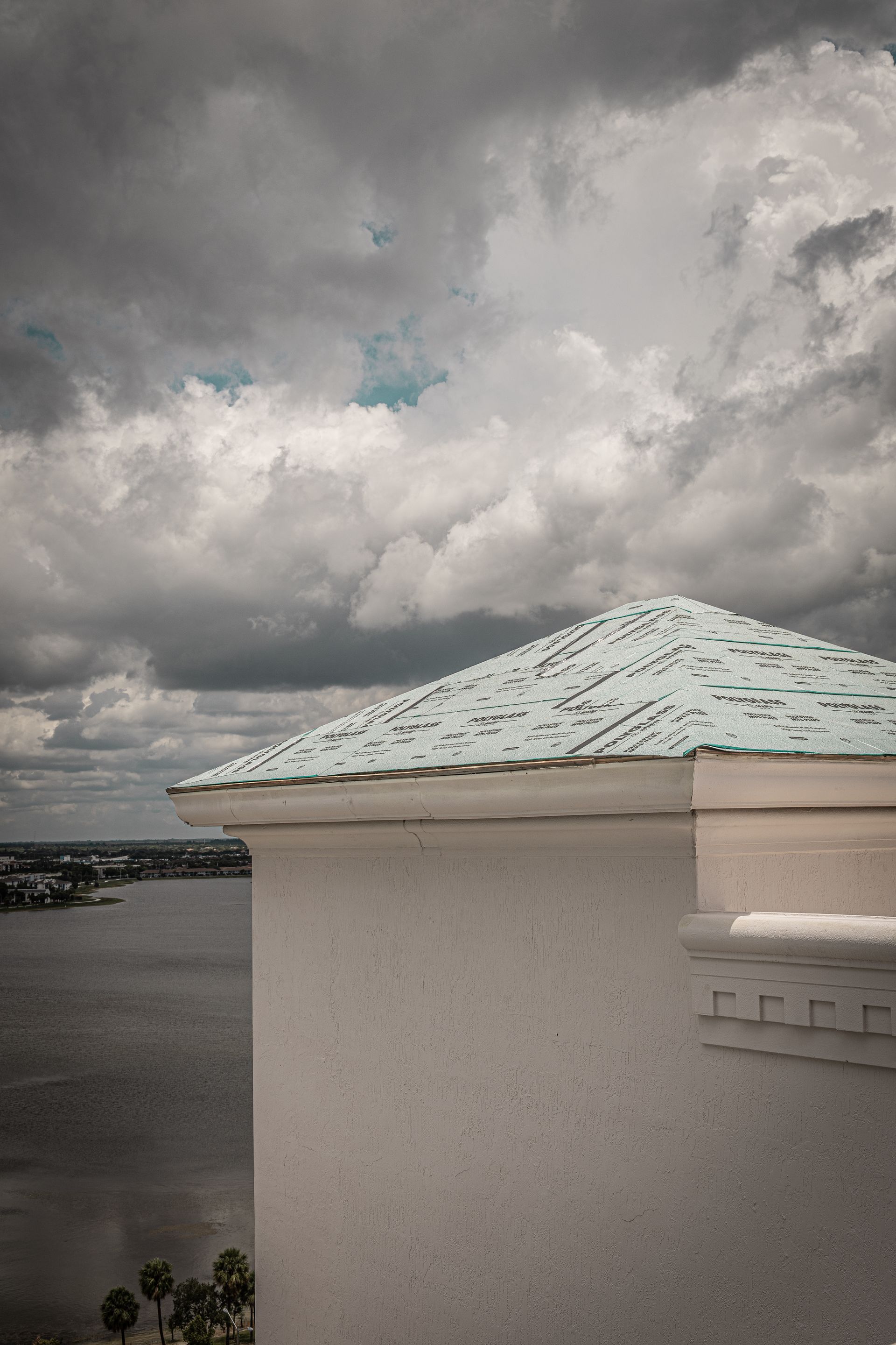 A white building with a blue roof and a cloudy sky in the background.