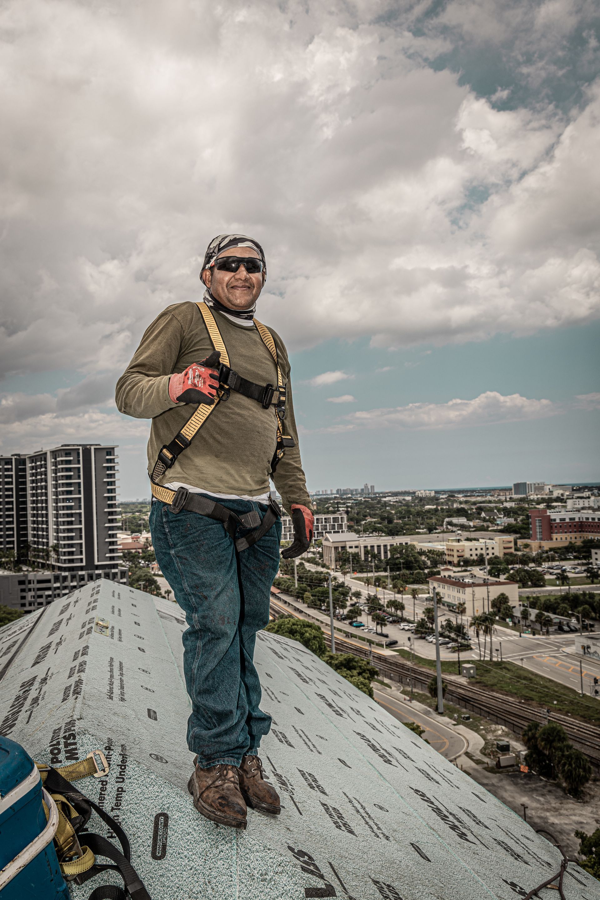 A man is standing on top of a roof with a city in the background.