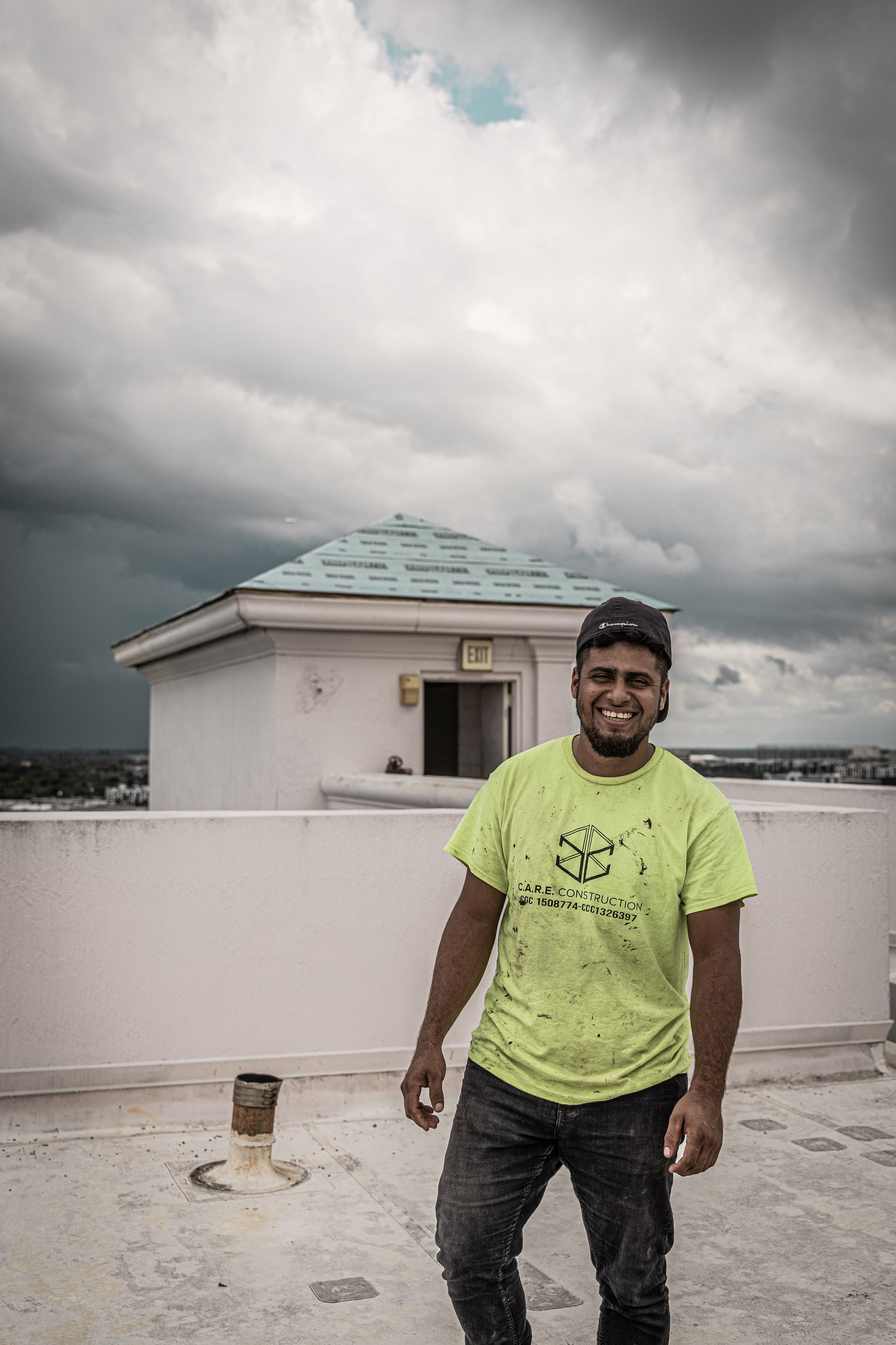 A man in a neon green shirt is standing on a roof.