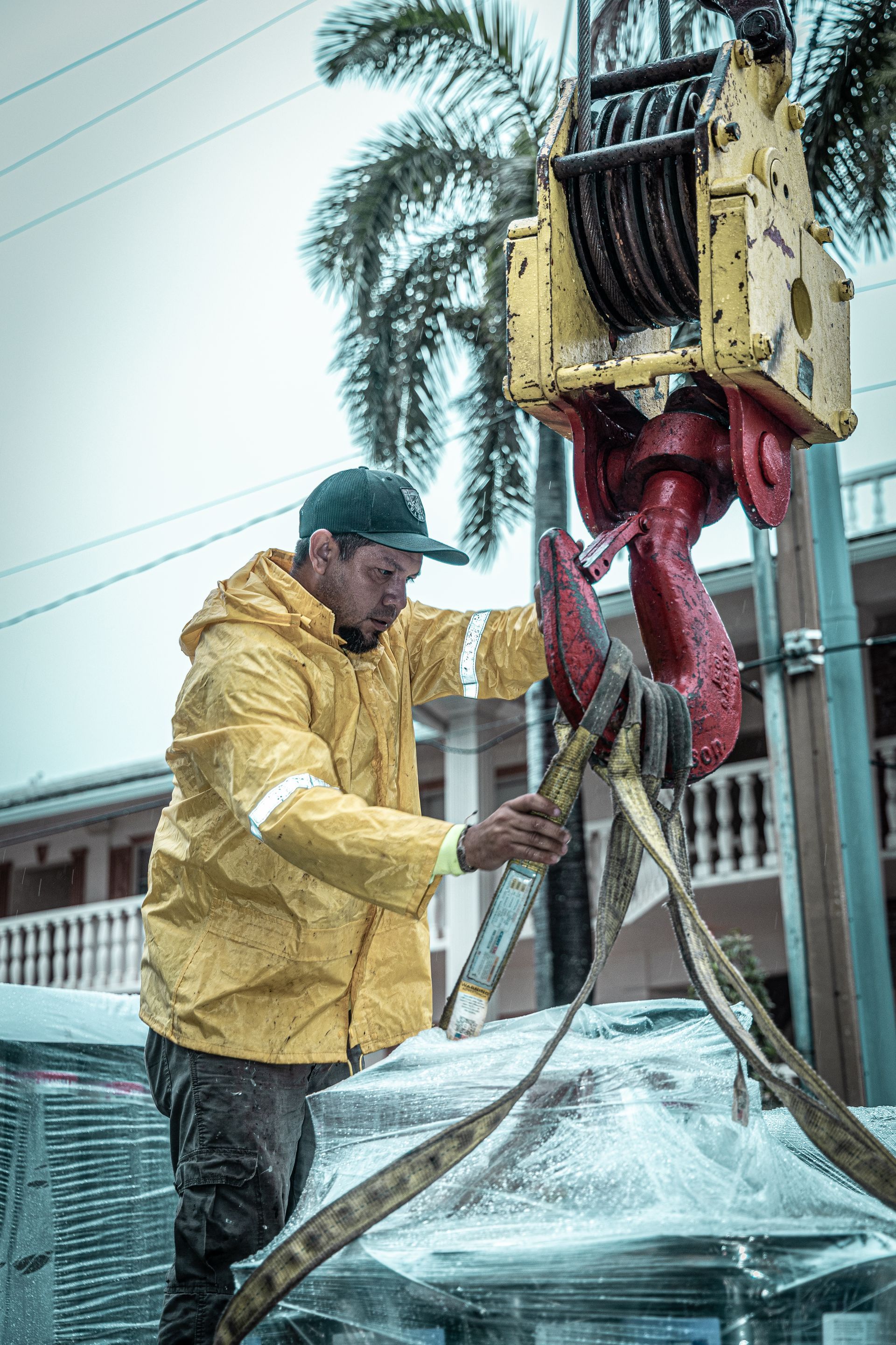 A man in a yellow jacket is working on a crane.