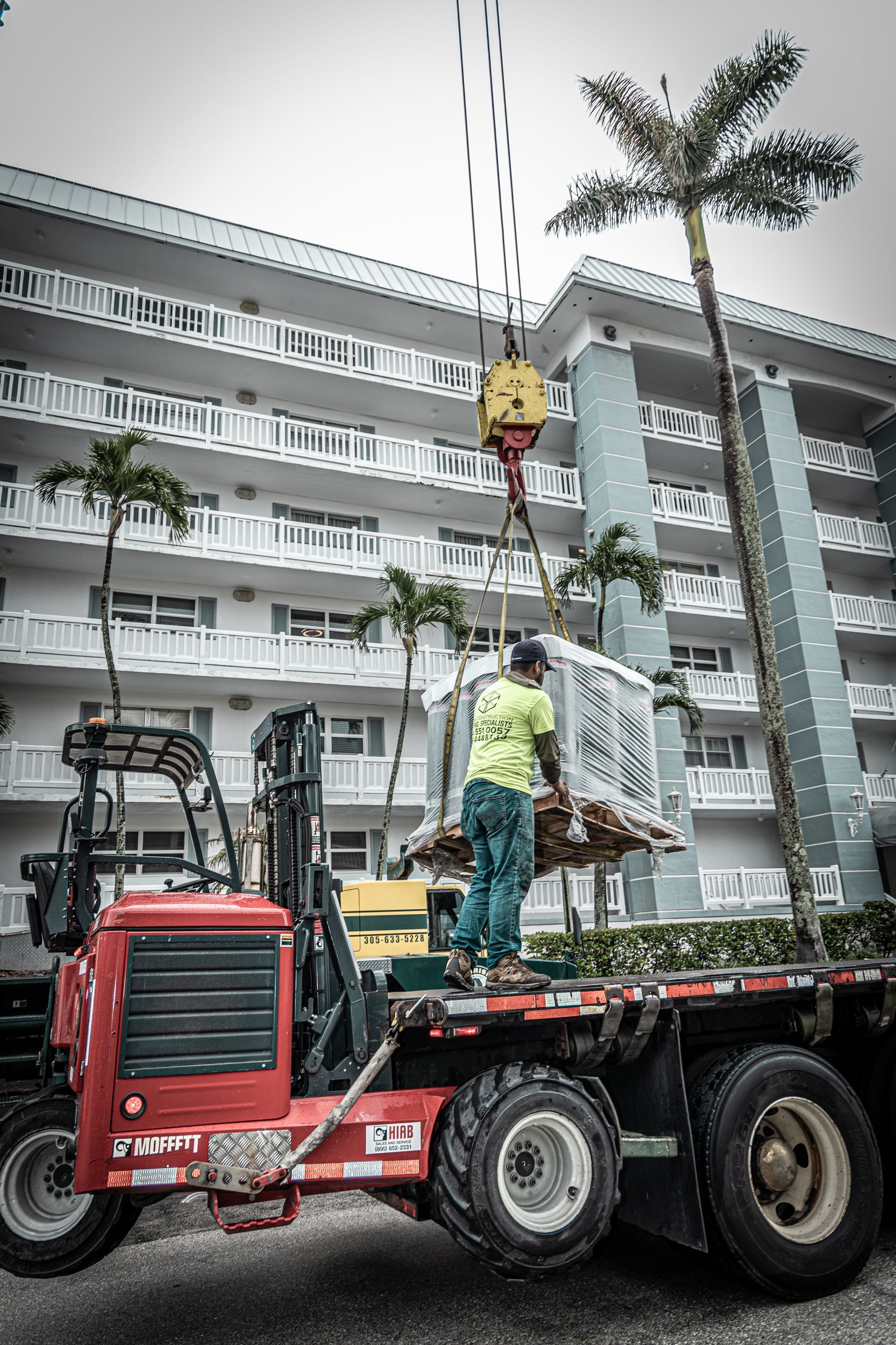 A man is standing on the back of a flatbed truck.