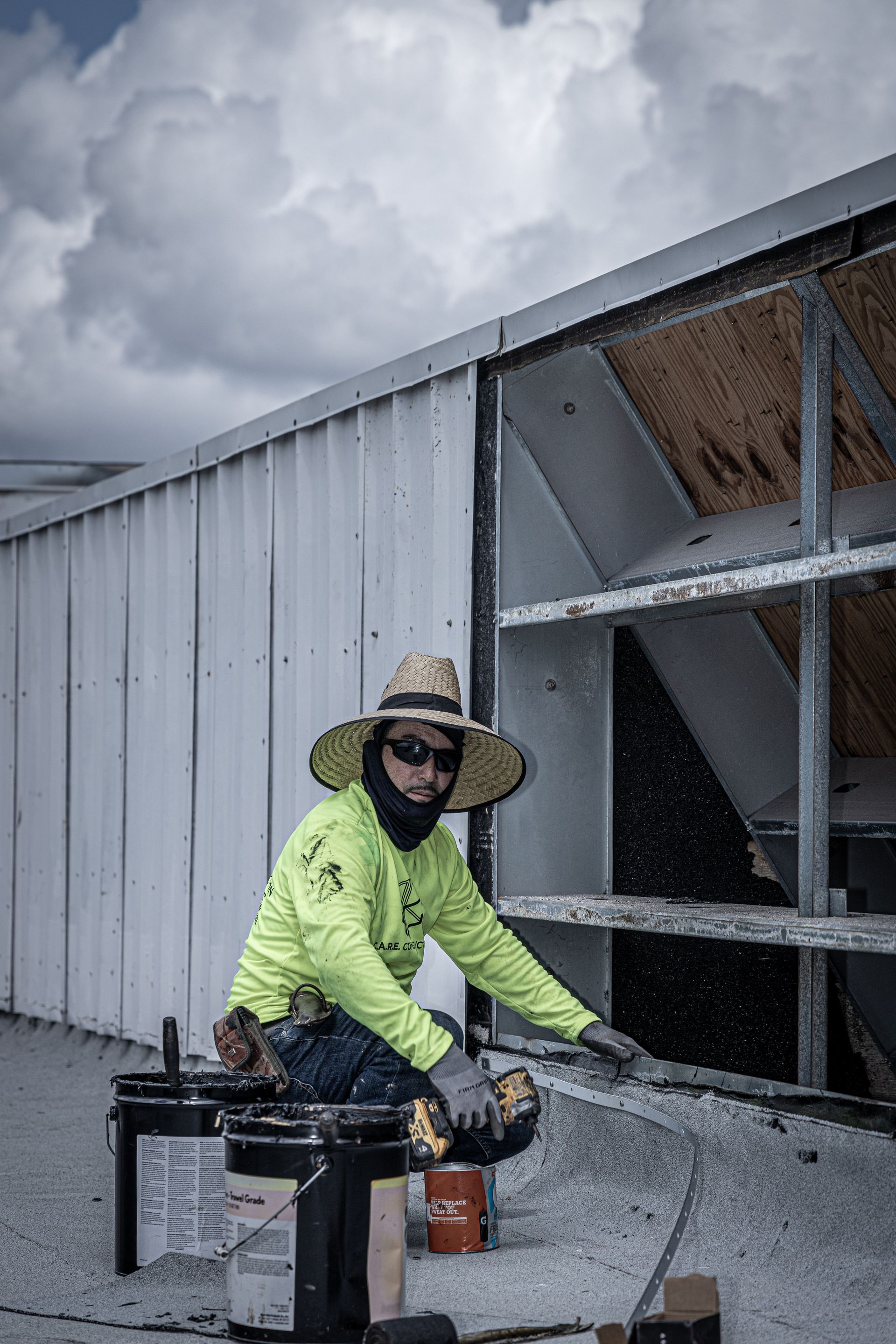 A man wearing a hat and sunglasses is working on a roof.