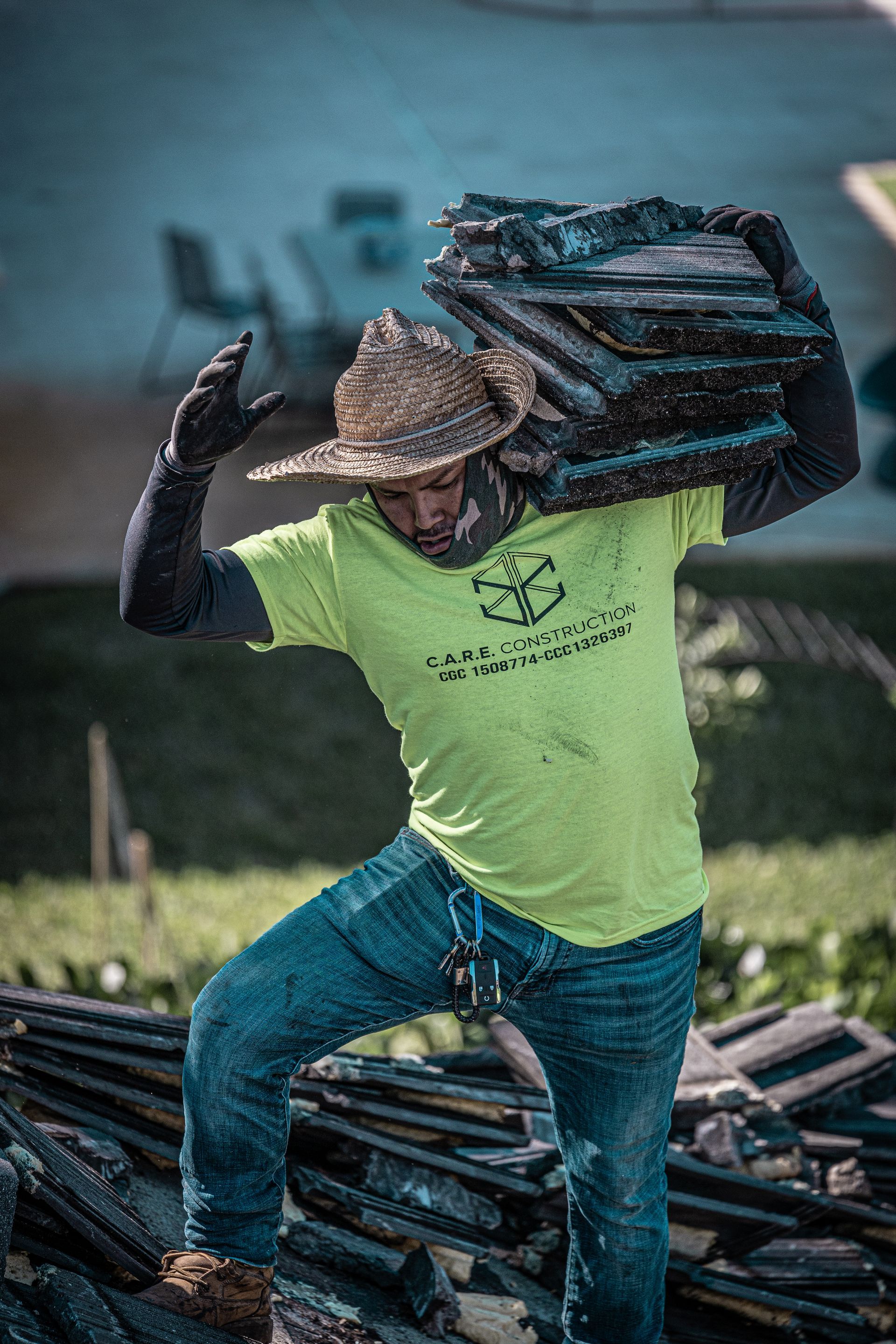 A man is carrying a stack of wood on his shoulder.